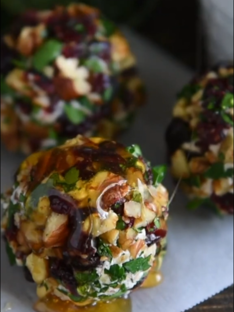 @thenovicechef These festive Cranberry Pecan Goat Cheese Truffles are a perfect make ahead holiday appetizer! Loaded with creamy goat cheese, cinnamon, cranberries and crunchy pecans, these mini cheese balls are always one of the first appetizers to go. Plus, they only take 15 minutes to make! 10 oz goat cheese 6 oz cream cheese 2 teaspoons cinnamon 3 tablespoons honey, plus extra for garnish 1 1/2 cups diced pecans 1 cup diced dried cranberries 1/2 cup minced fresh parsley In a large bowl, beat together the goat cheese, cream cheese, cinnamon and honey until light and fluffy. Add 1/2 cup pecan chips, folding to combine. Set aside. Line your countertop with parchment paper. Toss together remaining pecan chips, dried cranberries and parsley in the center of the parchment paper. Using a large cookie scoop, scoop out one round of cheese filling and toss in the cranberry/pecan mixture. Continue until all truffles have been rolled in coating. (If you have any questions, watch the video in this recipe card to see how I easily do this.) Refrigerate cheeseballs until ready to serve. You can make these up to three days before, just make sure and store them in an airtight container in the refrigerator. To Serve: Drizzle truffles with honey, if desired. Serve with crackers, warm crostini or as is with a toothpick (or pretzel stick)!