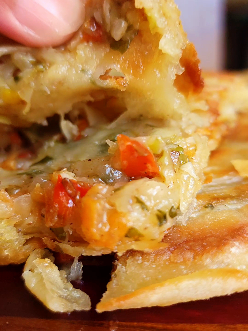 Pepper Roti Made with Gold Star Pure Vegetable Ghee Ingredients For the Paratha Dough (Loya Preparation): Prepared paratha dough (loyas) (see previously posted recipe) Gold Star Pure Vegetable Ghee Ground chadon beni and garlic For the Filling: 1 medium hot pepper (or to taste), finely chopped 1 medium onion, finely chopped 5 cloves garlic, finely chopped 3–5 pimentos, finely chopped Chadon beni (culantro), finely chopped 1 medium raw aloo/potato, peeled and grated 1 medium carrot, grated ½ cup grated or finely chopped red sweet (bell) pepper ½ tsp salt (or to taste) – add only when ready to fill 1 tsp roasted ground geera/cumin Grated cheese (amount to preference) For Cooking: Gold Star Pure Vegetable Ghee for spreading and cooking Additional ghee mixed with remaining chopped seasonings (from above) Method Step 1: Prepare the Paratha Loya Roll out the loya and spread a mixture of ghee, ground chadon beni, and garlic. Sprinkle lightly with flour. Make a cut from the center to the edge. Roll into a cone shape and tuck the end into the bottom of the cone. Flatten the top gently. Cover and rest for at least 40 minutes. Step 2: Prepare the Filling Finely chop hot peppers, pimentos, onion, garlic, and chadon beni. Add half of this chopped seasoning mix to a bowl with the grated potato, carrot, and sweet pepper. Season with roasted ground geera/cumin and salt (add salt only when ready to fill to prevent the vegetables from releasing water). Add the other half of the chopped seasoning to the seasoned ghee previously used when rolling the paratha. Step 3: Assemble the Pepper Roti Roll out the rested paratha loya. Spread the seasoned ghee over half of the surface. Evenly layer the vegetable filling over the ghee. Sprinkle with grated cheese. Fold the unfilled half over the filled half, similar to a calzone. (Traditionally, you can fill the entire roti and use another thinly rolled out loya to place over to seal, this method is a little easier to handle) Seal or crimp the edges securely. Step 4: Cook the Pepper Roti Place the filled roti on a hot, greased tawah over medium-low heat. Cook for about 10 minutes, spreading ghee on the top. Flip and continue cooking, adding ghee as needed. Cook until both sides are golden, crisp, and the roti is fully cooked through. Step 5: Serve Remove from tawah. Cut into slices. Serve piping hot and enjoy! #pepperroti #diwalirecipes #trinitiktok  @Persad’s D Food King 