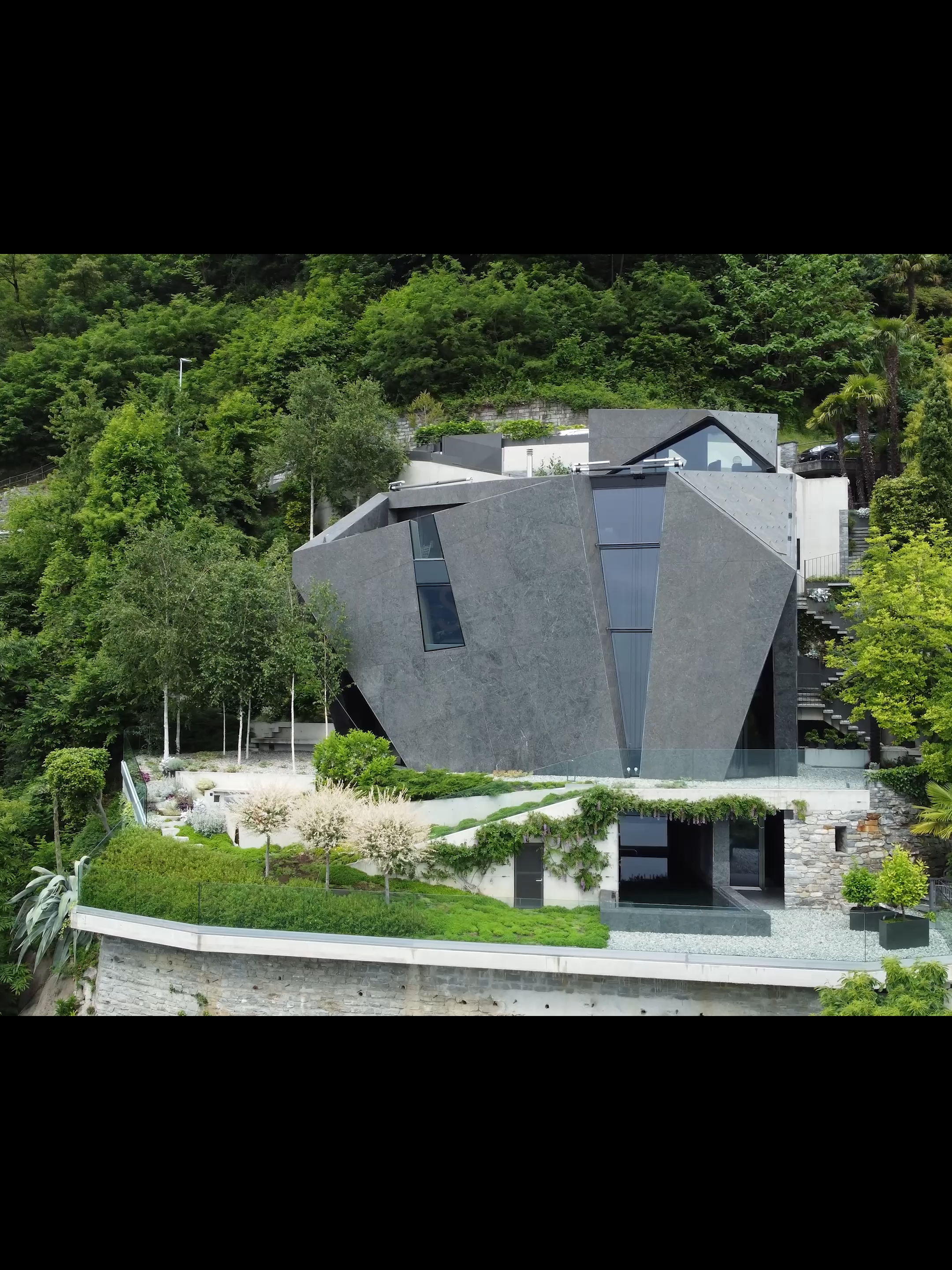 Villa Sangha - Forni & Gueli Architetti Spigolosa e particolare rappresenta una sfida estetica, ma allo stesso tempo dona all’edificio un look unico ed elegante. Il progetto degli architetti s’inserisce nel contesto del paesaggio e non cela la sua similitudine con uno spuntone di roccia delle alpi svizzere. La casa è rivestita in pietra ed è una ottima scelta per chi desidera una casa moderna ma con un tocco di eleganza classica. Questo materiale conferisce all’edificio un aspetto piacevole, rendendolo resistente alle intemperie e all’usura del tempo. Il materiale scelto offre una varietà di colori e texture e viene usata sia all’interno che all’esterno della villa. La pietra è sia elemento decorativo che funzionale. Architetto Progettista: Fausto Forni e Stefano Gueli Studio di Architettura:  Forni & Gueli Architetti Nome progetto: Villa Sangha Video di: Urbana Production Produzione di: Architettura Urbana  #svizzera #casamoderna #villamoderna #villadilusso #homedesign