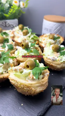 Cine zice că aperitivele nu pot fi și frumușele și delicioase și sunt perfecte pentru musafiri, picnicuri sau doar când ai chef de ceva bun, fără efort? #fyp #foryou #viral #ionelaskitchen  Pentru această rețetă eu am folosit un foietaj dreptunghiular din comerț și l-am porționat exact așa cum vedeți că am procedat în video. Apoi am întins ușor fiecare foaie și am îmbrăcat toată tava de brioșe. Până unde ajung aperitivele mele? Scrie orașul tău. Am procedat exact la fel cu toate celelalte, sigilându-le foarte bine, după care le-am uns cu un gălbenuș de ou și două linguri de lapte. Apoi le-am presărat cu semințe de susan sau oricare semințe vă plac și le-am introdus la cuptorul preîncălzit la osutaoopțig de grade, aproximativ doisprezece minute. După ce le-am scos de la cuptor, le-am lăsat la răcit zece minute, apoi le-am îndepărtat din forme, iar umplutura este la alegerea voastră. Eu am preparat o salată din piept de pui și am folosit osută de grame de salată verde, douăsute de grame de piept de pui, osută de grame de boabe de porumb dulce, iar pentru sos am folosit osută de grame de iaurt natural, o lingură de maioneză, sare, piper, praf de usturoi și zeama la jumătate de lămâie. Am pus dressingul peste toate aceste ingrediente și am încorporat ușor. Vă invit și pe canalul meu de YouTube Ionela's Kitchen, cu cele mai delicioase rețete de prăjituri. Vă mulțumesc! Iar rezultatul? Crocante, răcoroase și pline de gust sunt un succes garantat la orice masă. Să vă fie de folos și urmăriți-mă pentru rețete rafinate și inspirație culinară constantă. Poftă bună!