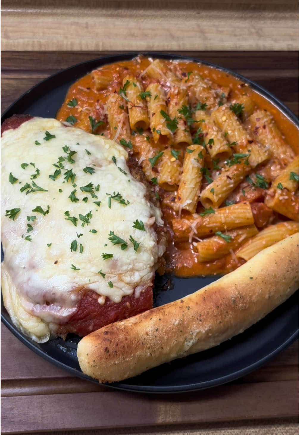 Chicken parmesean with rigatoni à la vodka & breadsticks❤️‍🔥 • • This is my first time doing a voiceover lol, idk do we like this style videos more??  • • INSTRUCIONES:  Empieza añadiendo pan rallado italiano a un bol y en otro, rompe y revuelve tres huevos. Toma la pechuga de pollo cortada en rodajas finas y sazona con; paprika, cebolla en polvo, ajo en polvo, pimienta negra y un poco de hojuelas de pimiento rojo triturado. Añade el pollo a la mezcla húmeda y luego a la seca. Fríe a fuego alto durante 10 minutos. En una olla, añade un poco de agua y deja que hierva. Luego, añade un poco de sal y la pasta. Deja que la pasta se cocine durante el tiempo recomendado en la caja. Saca el pollo de la sartén y colócalo en una fuente para horno. Cúbrelo con salsa Mariana, más queso parmesano y mozzarella rallada. Hornea a 350°F (175°C) durante 30 minutos. Una vez que la pasta esté lista y hayas escurrido el agua, añade la salsa de vodka.  Añade 1/2 bloque de queso crema, 1/2 taza de queso parmesano, mezcla bien y deja hervir a fuego lento durante 10 minutos. Listo para servir!  Yo le puse perejil fresco picado encima. #chickenparm #Recipe #ideasdecomida #recetastiktok #Foodie 
