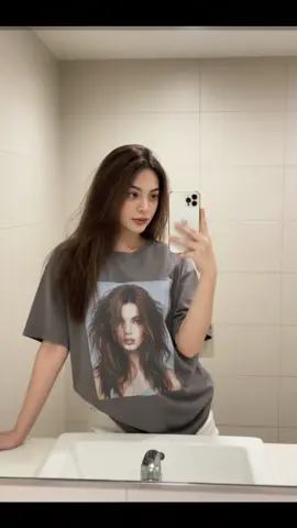 #CapCut #tiktokviral #ai #gemini #fyp  Gemini ai Prompt 🔥👇 Using the uploaded image, do not alter her face. Create A mirror selfie of a beautiful young woman inside a large bathroom. She is holding a white iPhone 14 Pro Max in one hand while looking at the camera with a seductive, alluring gaze. Her other hand is resting on the bathroom sink counter. She is wearing an oversized gray t-shirt with a large printed graphic of a woman with messy hair that falls slightly below the shoulders. She pairs this with white shorts that are partly visible under the loose shirt. She has long, slightly messy brown hair that cascades over her shoulders and down her back. The bathroom interior is spacious, with clean, light-colored tiles and a large mirror reflecting her full upper body. The lighting is bright and evenly distributed, enhancing the clarity of her features and outfit. Her pose is casual yet confident, capturing a natural yet captivating aesthetic. Include realistic lighting, subtle shadows, soft skin texture, and reflective details from the mirror and sink.