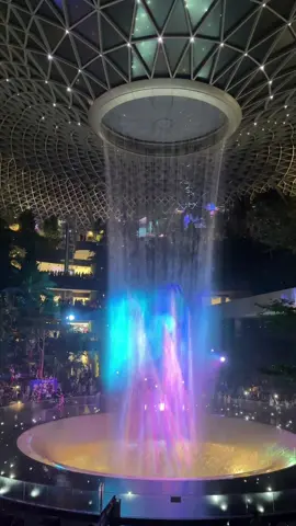 The Rain Vortex at Jewel Changi Airport has a light show every day at 8 PM and 9 PM.  The light and music showcase is a nightly event that transforms the waterfall into a dazzling display.   #fyp #changiairport #singapore #holiday #travel 