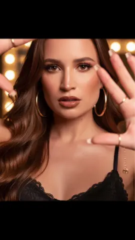 Fotos gemini ! Prompt- Crie um retrato em close-up ultra-realista de uma jovem autoconfiante com cabelos cor chocolate  longos, volumosos e ondulados e pele radiante e impecável. Ela está vestindo uma blusa de renda preta com espaguete. Ela olha poderosamente para a câmera com olhos ardentes. Grandes crioulos dourados emolduram seu rosto enquanto os anéis dourados capturam a luz.. O fundo é suavemente iluminado com tons quentes que enfatizam a profundidade e o foco em seu rosto. Filmado com lente de 85 mm, profundidade de campo rasa, iluminação cinematográfica, High-Fashion-Photography-aesthetics, 4K-Ultra-HD- Klarheit. A maquiagem é expressiva: cílios naturais longos e pretos, delineador, iluminador, contornos fortes e blush, pele impecável e lábios volumosos castanhos brilhantes com delineador de lábios marrom escuro. Sobrancelhas bem cuidadas withBrauenlifting-Effekt. (Mantenha as características faciais como estão.) Unhas compridas em baby boomers. Ele usa um brinco combinando e vários anéis, charme - corrente de braço. #gemini #aiprompt #viraltiktok 