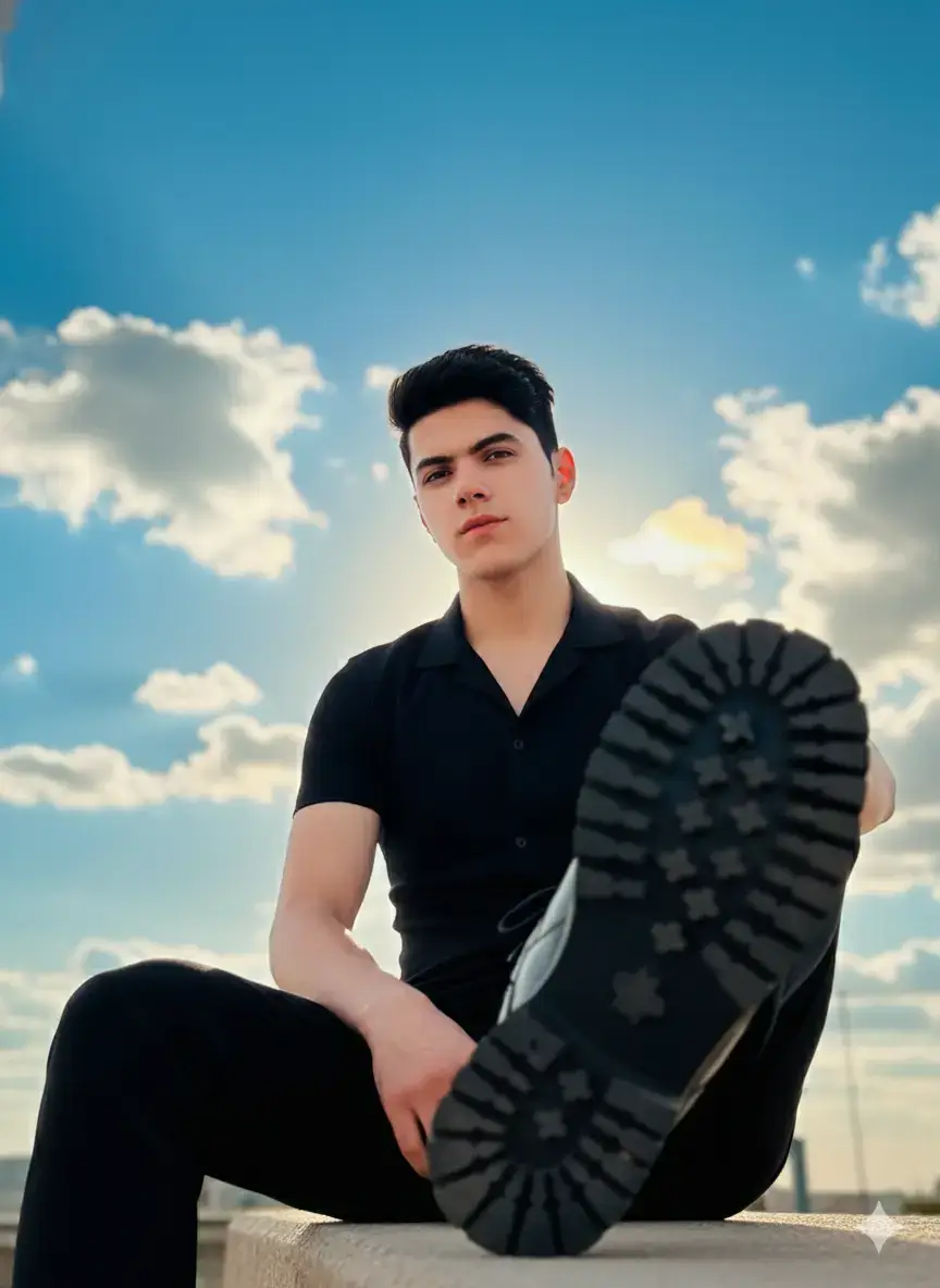 #منتظر_المنصوري™️ Retrato fotográfico ultrarrealista em 8K de um homem com o mesmo rosto da imagem de referência (sem alterações faciais). Ele está sentado em um ambiente ao ar livre, com o céu azul e nuvens iluminadas pelo sol atrás dele. Usa roupa preta ajustada e botas de sola grossa, com uma das pernas estendida para frente em primeiro plano, destacando a sola da bota com foco cinematográfico. A iluminação é natural, vinda do pôr do sol, criando um halo suave de luz ao redor do cabelo