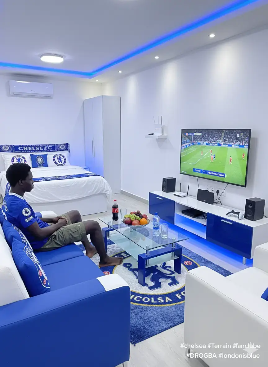 Tout ce qui aime leur club, voici le prompt ou le texte pour créer une photographie où portrait. Moi mon club c'est Chelsea Football Club Pour réaliser cette photographie, vous changez juste les couleurs de mon club à celle de votre club merci. NB : Svp le prompt où le texte est en commentaire pour réaliser la photographie merci. LE PROMPT OU LE TEXTE Créez un portrait de ma photo la scène se déroule dans un studio d'appartement au design moderne, orienté sur le thème de Chelsea FC. Moi-même : Je suis assis confortablement sur un fauteuil à deux places, revêtus des couleurs de Chelsea (bleu roi et blanc). Je porte le magnifique maillot de Chelsea pour la saison 25/26, associé à un short de style militaire. Je suis pieds nus, sans chaussures, pour une ambiance décontractée à la maison. Mon expression est concentrée sur le match. Le Décor du Salon: Murs et Plafond : Les murs du salon sont peints en blanc éclatant. Le plafond présente un design moderne avec des moulures et des éclairages indirects grâce à des bandes de LED bleues, créant une ambiance immersive. Meubles TV : Le meuble de télévision, légèrement long et de couleur Chelsea (probablement bleu avec des touches blanches), est doté de LED bleues pour un éclairage d'ambiance. Télévision : Un grand écran plat de 55 pouces est fixé au mur. Il affiche clairement un match de football entre Nottingham Forest et Chelsea. Le bandeau de score en bas de l'écran indique : Chelsea 3 - 1 Nottingham Forest. Assises : Le fauteuil à deux places sur lequel je suis assis est bleu/blanc Chelsea. Juste à côté, un fauteuil simple est d'un blanc pur. Table Vitrine : Une table basse vitrine, aux couleurs de Chelsea (cadre bleu, peut-être), trône au centre. Dessus, un plat contient des fruits frais bien disposés (pommes rouges, oranges et raisins verts/violets). À côté, une bouteille de Coca-Cola et une bouteille d'eau minérale sont prêtes, avec deux verres. Tapis: Un tapis de salon moelleux aux couleurs de Chelsea est étendu sur le sol, arborant fièrement le logo du club au centre. Système Audio : Des baffles de marque Bose sont discrètement installées, assurant une qualité sonore immersive pour le match. Le Coin Chambre (à l'arrière): Le Lit : Un lit double est bien fait, avec des draps et une couette peints en blanc. Le couvre-lit (ou la couette) est joliment arrangé aux couleurs de Chelsea, tout comme les quelques oreillers décoratifs. Équipements et Technologie : Placard : Un placard blanc intégré est équipé de lumières LED bleues. Climatiseur : Un climatiseur blanc de marque Smart est visible. Wi-Fi: Une petite boîte Orange-Box Wi-Fi de couleur blanche avec l'écriture en orange est posée sur une étagère. Console de Jeux : Une console de jeux PlayStation 5 (PS5) est visible près du meuble TV avec les 2 manettes. Ne changez rien sur le visage. #chelsea #Terrain #fanclube #DROGBA #londonisblue