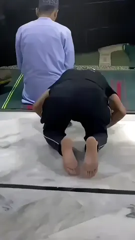 Seorang Pemuda lagi melaksanakan sholat pemuda tersebut memakai baju yang bertuliskan 