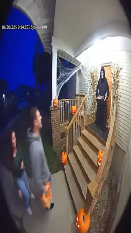 #halloween #viral #scareprank #halloweenlook #trickortreat  Sora2 Prompt: Nighttime, quiet suburban neighborhood. Ring doorbell camera POV, wide fisheye lens, timestamp overlay, porch light glowing warm orange. The house has a tall wooden porch with eight wide steps leading to a short walkway. The porch is decorated with jack-o’-lanterns, cobwebs, and a grim reaper statue beside the door, holding a candy bowl in one skeletal hand. The statue stands completely still, cloaked in black, face hidden under the hood. A man and woman in their 30s walk up from the sidewalk. They’re laughing softly, both dressed casually — jeans, hoodies, relaxed posture. The man carries a candy bag, the woman follows a step behind, filming on her phone. They stop at the top. The woman whispers, “That thing looks real.” The man grins, “It’s fake,” and reaches for candy. Suddenly, the grim reaper JERKS forward, arms swinging slightly, head snapping up, eyes flashing red as it emits a deep mechanical growl. The man screams, jumps backward, and loses his footing. As he falls, he instinctively grabs the woman’s hair for balance. She screams in shock as he pulls her down with him. They tumble down the entire staircase, bumping and sliding in real physical motion, limbs flailing, candy spilling. They land on the grass below, tangled together. A second of silence. Then the woman bursts into hysterical laughter, gasping for air and clutching her stomach. The man starts laughing too, still on his back, pointing at the porch in disbelief. The Ring camera remains fixed the entire time, showing everything in realistic 4K low-light, 30fps exposure, natural shadows, detailed stair-fall physics, and authentic audio timing with screams and laughter. Tone: Halloween realism with a sharp scare, real stumble, hair-grab chaos, and hysterical laughter ending.
