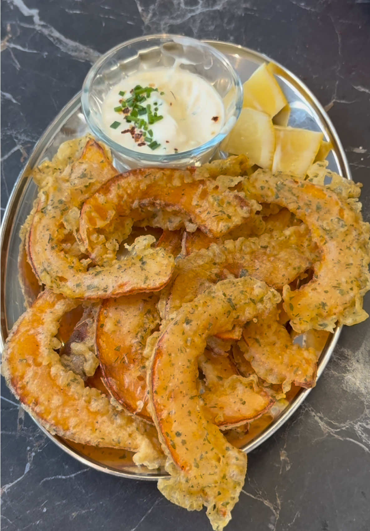  Cette recette, c’est le rituel de mes apéros d’automne. Des tranches de potimarron frites, croustillantes à souhait, avec une sauce citron-crème fraîche ultra fraîche et acidulée. Mes potes ne viennent plus pour moi, ils viennent pour ça 😏 ✨ Ingrédients (pour 4 personnes) Pour les beignets de potimarron : * 1 petit potimarron * 80 g de farine * 20 g de maïzena (ou farine de riz) * 1 c. à café de cumin * 1 c. à café de coriandre moulue * ½ c. à café de paprika * 1 pincée de sel * 120 ml d’eau gazeuse bien fraîche * Huile neutre pour la friture Pour la sauce : * 100 g de crème crue (ou crème épaisse) * Le jus d’½ citron * 1 petite gousse d’ail râpée * 1 c. à soupe de ciboulette ciselée * Sel, poivre 👩‍🍳 Préparation 1. Coupe ton potimarron en deux, retire les graines et tranche-le finement à la mandoline (attention les doigts 😅). 2. Dans un bol, mélange la farine, la maïzena, les épices et le sel. 3. Ajoute l’eau gazeuse petit à petit — elle rend la pâte plus légère et croustillante que l’eau plate. 4. Trempe les tranches de potimarron dans la pâte, puis fais-les frire dans une poêle avec de l’huile neutre, jusqu’à ce qu’elles soient bien dorées. 5. Pendant ce temps, prépare la sauce : mélange la crème, le citron, l’ail, la ciboulette, sel et poivre. 6. Servez le tout bien chaud, à tremper sans modération. 🧡 C’est croustillant, fondant, acidulé, réconfortant… bref, l’apéro parfait d’automne. Tu fais goûter ça une fois, et on t’en reparle tout l’hiver. 😏✨  