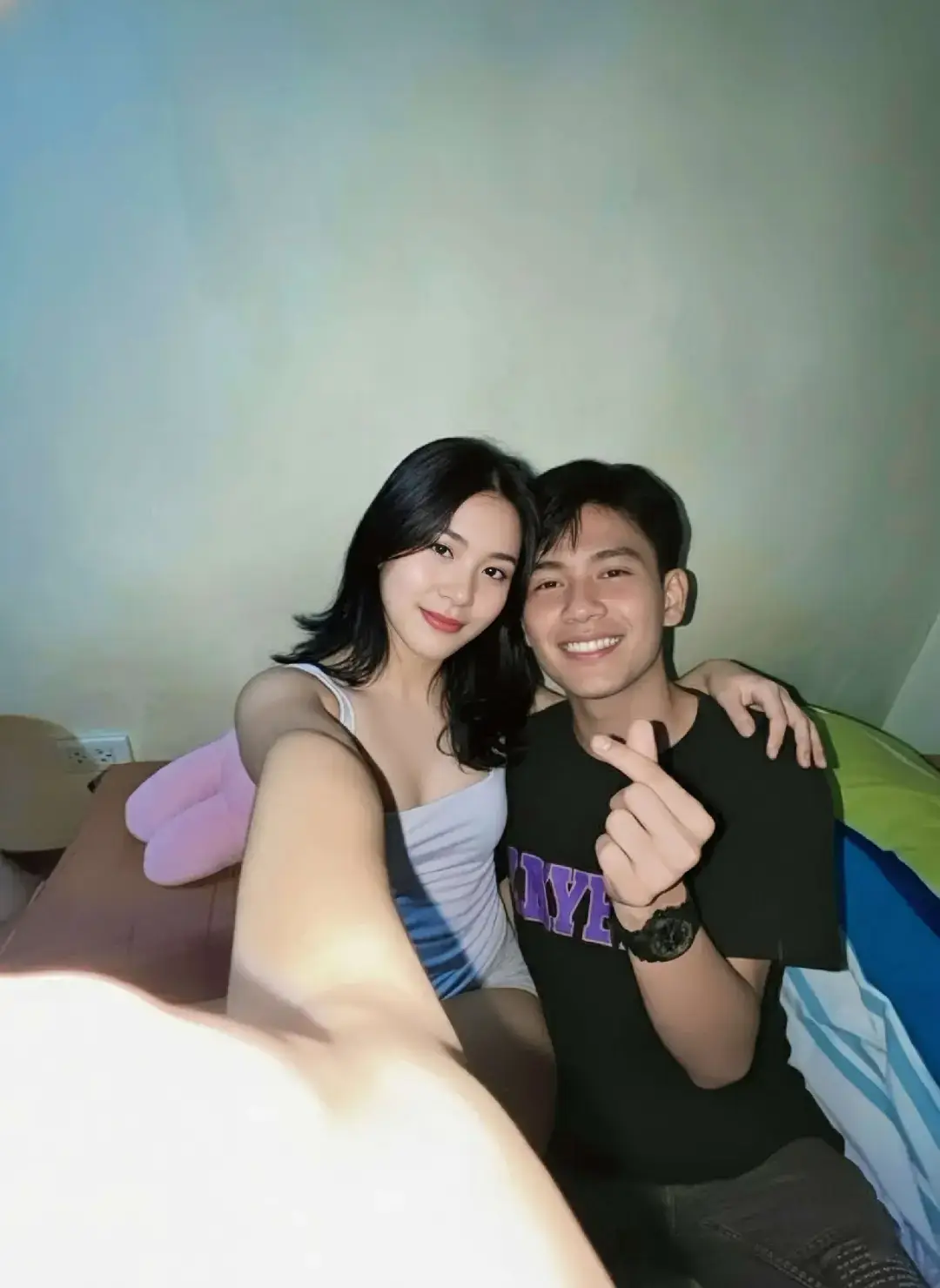 BACA CAPTION‼️ 1. Buka google/apk gemini di hp kalian 2. Masukan photo wajah kalian dan pastekan  prompt:👇🏻 Coba buatkan sebuah potret selfie jarak dekat yang memancarkan kehangatan dan keintiman dari dua subjek tersebut, menampilkan sepasang muda-mudi yang ceria. Di sisi kiri, seorang wanita muda dengan rambut hitam legam bergelombang lembut hingga sebahu, mengenakan tank top berwarna terang (putih susu atau abu-abu pucat) yang menonjolkan kulitnya yang bersih, menatap langsung ke kamera dengan senyum tipis dan mata yang berbinar lembut. Ia condong sedikit ke depan, menampilkan pose yang santai namun anggun.  Di samping kanannya, seorang pria muda dengan potongan rambut hitam rapi, mengenakan kaus oblong berwarna arang gelap atau ungu tua dengan desain samar di bagian dada, merangkul bahu wanita tersebut dengan gesture protektif namun lembut. Ia menampilkan senyum lebar yang tulus dan bersemangat, sambil membentuk tanda hati kecil dengan ibu jari dan telunjuknya di depan dadanya, seolah mengirimkan pesan kasih sayang. Pergelangan tangannya dihiasi jam tangan digital berwarna gelap. Keduanya duduk berdampingan di atas permukaan yang empuk, mungkin alas tidur atau sofa berwarna cokelat hangat, yang sedikit terlihat di bagian bawah foto.  Latar belakangnya sederhana namun efektif: sebuah dinding polos berwarna krem atau putih gading yang memberikan kesan clean. Di sisi kanan bawah, terlihat sebagian kecil dari sebuah struktur berwarna-warni – kemungkinan tenda kemah mini dengan aksen hijau terang dan biru laut, serta sedikit sentuhan putih. Di sisi kiri, bantal atau boneka berbentuk lucu berwarna baby pink tergeletak santai, menambah sentuhan domestik.  Pencahayaan dalam ruangan sangat dominan dari arah depan atas, menciptakan efek yang sedikit overexposed namun disengaja, memberikan suasana cerah dan fokus yang tajam pada subjek. Cahaya kekuningan yang lembut menyelimuti adegan, menonjolkan kilau pada rambut dan kulit mereka, serta menciptakan aura keakraban dan kebahagiaan yang menawan. Foto ini terasa seperti diambil di malam hari, menciptakan suasana pribadi dan tenang. 3. Tunggu hasilnya 4. Kalo sudah sesuai Download nahh sekarang kamu udh ngga bakal dihina lagi Bree  #prompt #geminiai  #masukberandafyp #zeepruk #fyp 