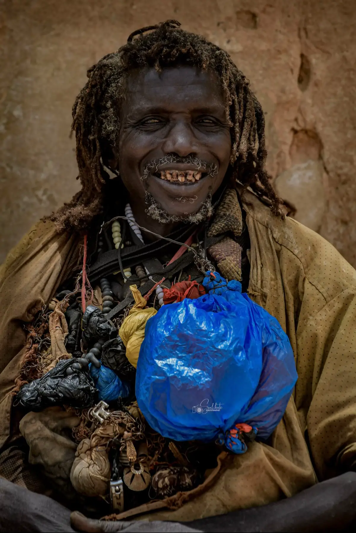 Il y a trois ans, à Touba, j’ai pris cette photo. Ce jour-là, j’ai croisé un vieux monsieur, assis dans le calme d’un lieu où le temps semblait s’être arrêté. Son regard portait la paix, et son air innocent disait plus que les mots. Quand je lui ai demandé la permission de le photographier, il a simplement hoché la tête, avec une bienveillance désarmante. Dans un monde où tout s’échange, lui m’a offert ce moment sans rien demander. Je n’ai eu qu’à déclencher — le reste, c’est son âme que l’image a retenue. Cette photo, je l’avais perdue. Et aujourd’hui, elle revient comme un signe, comme un souvenir que le destin me ramène, pour me rappeler que certaines lumières ne s’éteignent jamais. #salihatephotographe 