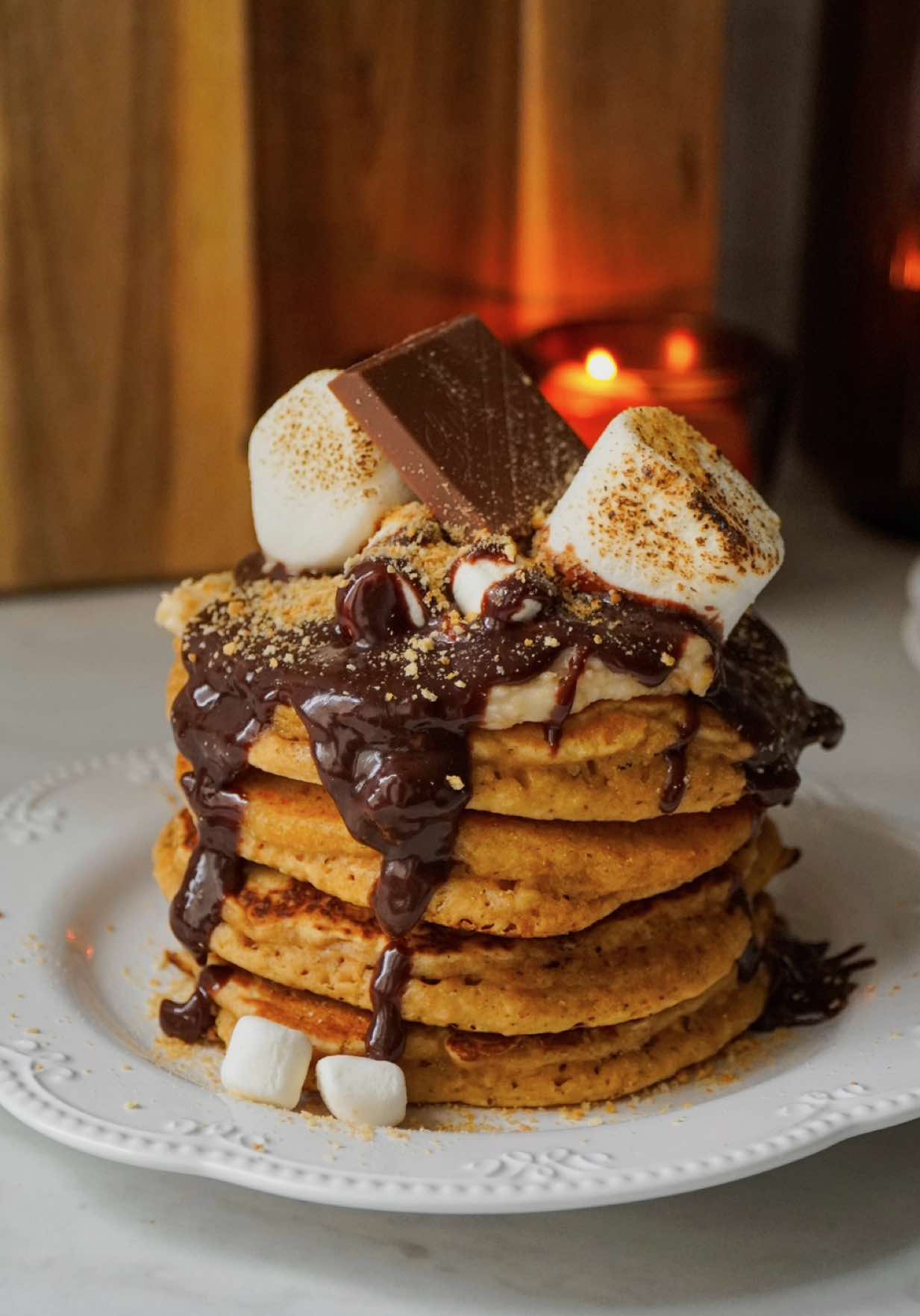 S’mores pancakes 🥞🍫🐻🤎☁️ -  Ingredients (For 8 Pancakes) For the pancakes: - 230g all purpose flour - 1 cup + 3/4 cup + 1 tablespoon  - 50g finely crushed graham crackers - 1/3 cup + 1 tablespoon  - 6g baking powder - 1 teaspoon + 1/4 teaspoon  - 50g dark brown sugar - 1/4 cups - 1 package (8g) Bourbon vanilla sugar - 2 teaspoons  - 1 large egg - 250g milk - 1 cup + 2 teaspoons - 35g melted butter - 2 tablespoons + 1 teaspoon  - 1 teaspoon vanilla extract For the frosting: - 120g Mascarpone Cream Cheese - 1/2 cup + 1 teaspoon  - 50g sugar - 1/4 cup  - 1 teaspoon vanilla extract or 1/2 teaspoon  - 15 finely crushed graham crackers - 2 tablespoons  For the chocolate ganache: - 100g milk chocolate chips - 2/3 cup - 40g heavy cream - 2 tablespoons + 2 teaspoons  Extras: - Marshmallows, for topping Instructions: 1. For the batter whisk together the flour, baking powder, finely crushed graham crackers and brown sugar. 2. Then add the egg, the milk, vanilla and melted butter. Mix until just combined. Overmixing the batter can lead to a though pancake. It’s okay if it’s lumpy. 3. Using an ice cream scoop or a laddle, scoop portions of batter (60g) into a non stick, buttered pan. 4. Cook over medium heat until bubbles appear on the top. Then flip and cook for an additional minute or two.  5. While you cook the pancakes, you can prepare the frosting and the chocolate ganache. 6. For the cream mix together the Mascarpone with the sugar until smooth and creamy.  7. Then add the finely crushed graham crackers along with the vanilla and mix until combined.  8. For the ganache heat the cream until it starts to simmer. 9. Pour it over the chocolate chips and let it sit for a few minutes, then stir until smooth. 10. Once everything is ready, assemble and enjoy!  #smores #pancakes #breakfast #brunchideas #asmr 