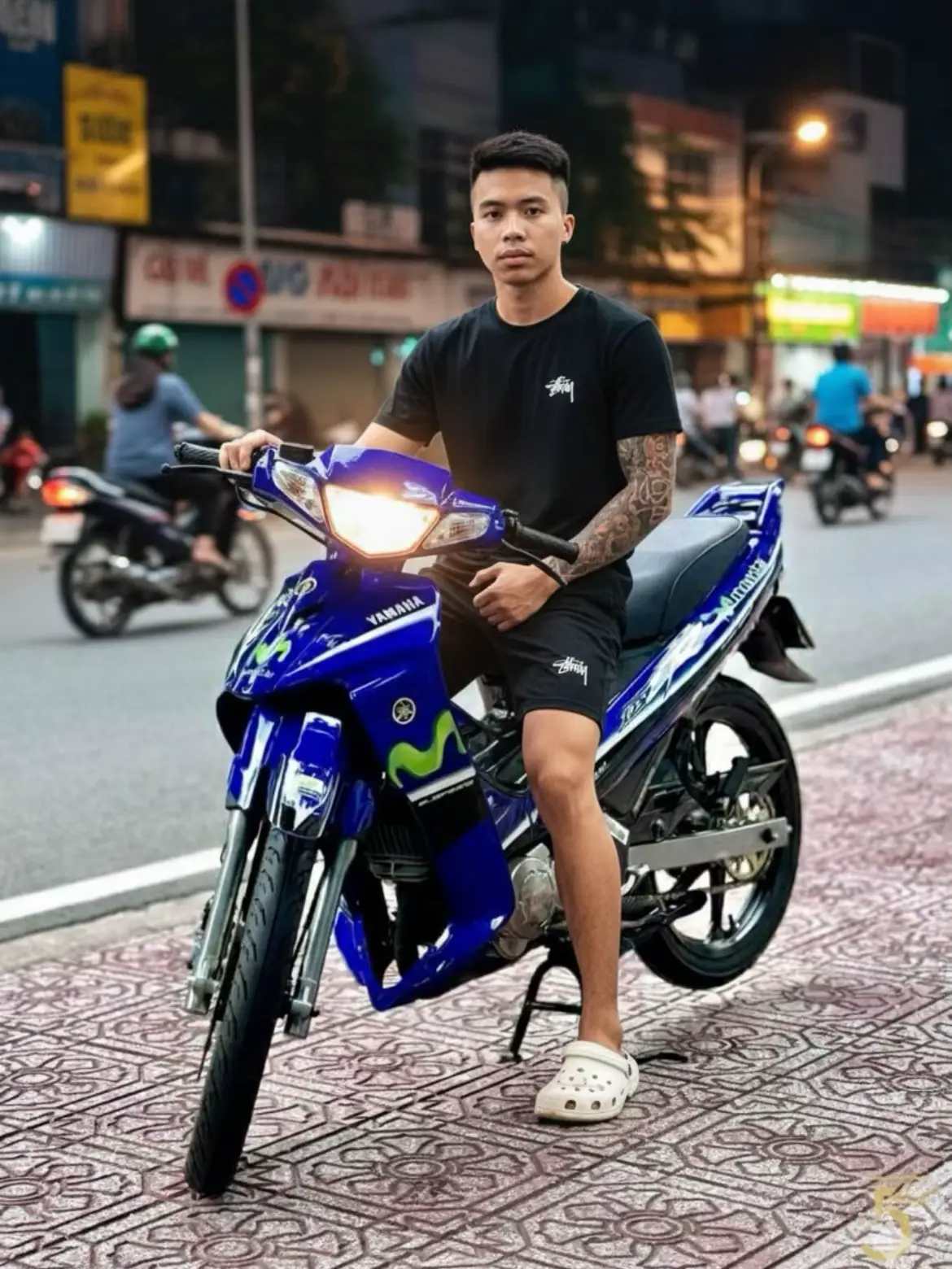 🪄 Create an image with Gemini Step 1: Open Google Gemini Step 2: Upload your image Step 3: Enter the prompt: A realistic photo of a young Vietnamese man sitting on a blue Yamaha Yaz 125 movistar motorbike parked on a Saigon sidewalk at night. He is about 1m60 tall, weighs 57kg, and has a slightly muscular, fit body from gym workouts. He wears a black Stussy T-shirt with a small logo on the chest corner, black shorts, and white Crocs. The motorbike's headlights are on, casting a soft light on the pavement. The background shows a typical Saigon street with warm artificial lighting, street signs, and a few blurred motorbikes passing by. The photo looks like it was taken with an iPhone in high resolution, with natural tones, realistic shadows, and slightly cinematic street-style composition. The lighting is bright and clear, giving the scene a vibrant, authentic feel, as if captured candidly in real life. #khanpromptai #GeminiAi #trending #viraltiktok #xuhuong 