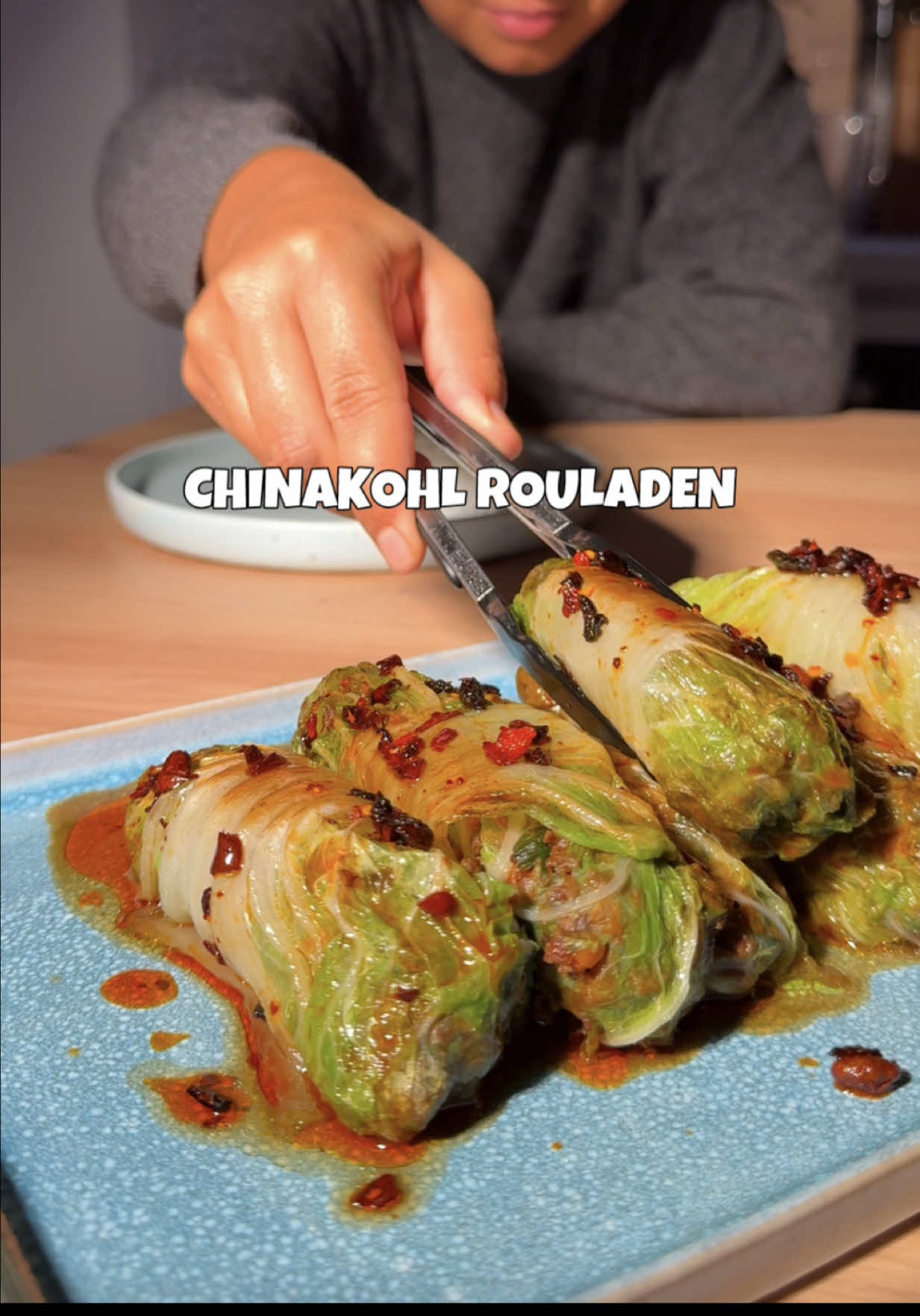 chinakohl-rouladen mit crispy-chili-öl ❤️‍🔥 es ist einfach YUM!  1 chinakohl (8 blätter) 2 karotten 1 bund lauchzwiebeln 1 stück ingwer 3 knoblauchzehen 10 pilze 1 packung v hack 3 EL dunkle sojasauce 2 EL sesamöl (geröstet) topping: crispy-chili-öl (kaufe ich von der marke „lao gan ma“) für die füllung das ganze gemüse fein hacken oder in einen zerkleinerer geben, dann mit etwas öl anbraten. zum schluss sojasoße und sesamöl hinzufügen. den strunk vom chinakohl entfernen und acht blätter abschneiden. gründlich waschen und in salzwasser 2–3 minuten blanchieren. die füllung in acht portionen aufteilen, auf die blätter geben und die seiten einklappen und einrollen. falls der chinakohl viele beschädigte blätter hat, einfach doppelt blätter legen. die rouladen in öl von beiden seiten anbraten, etwas wasser in die pfanne geben, den deckel drauf und 5–7 minuten dämpfen lassen. anschließend mit crispy chili öl und reis servieren. ❤️‍🔥