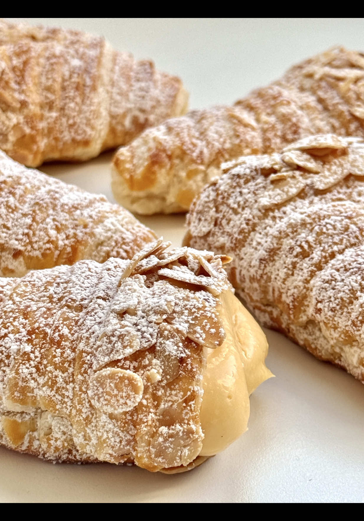 Ad | Orange Custard Crème Horns 🍊🤍 Delicate, golden puff pastry horns filled with silky orange pastry cream – crisp, creamy, and bursting with sunny freshness. 🥰 📝 Ingredients (makes about 5 large horns) For the pastry: • 1 sheet puff pastry (store-bought, chilled) • a little vegetable oil for greasing • 1 egg yolk • 1 tbsp milk • almond flakes for sprinkling For the orange pastry cream: • 200 ml milk (¾ cup + 1 tbsp) • 50 ml freshly squeezed orange juice (3 ½ tbsp) • 2 egg yolks • 40 g sugar (3 tbsp) • 20 g cornstarch (2 ½ tbsp) • 1 tsp vanilla extract • zest of ½ organic orange • 20 g butter, soft (1 ½ tbsp) For dusting: • powdered sugar 🤍 Instructions 	 1.	Preheat the oven to 200 °C / 390 °F (top/bottom heat). 	 2.	Lightly grease the horn molds with vegetable oil. For wider horns, place two molds side by side. 	 3.	Cut the puff pastry sheet into 2 cm (¾ in) wide strips from the short side. 	 4.	Wrap the strips around the molds, slightly overlapping, starting from the tip. 	 5.	Mix egg yolk and milk, brush the horns, and sprinkle the top area (about 2 cm / 1 in from the start) with almond flakes. 	 6.	Place on a parchment-lined baking sheet and bake for 15–18 minutes until golden brown. Carefully remove from the molds and let cool completely. 	 7.	For the orange pastry cream: Heat milk, orange juice, vanilla, and orange zest (do not boil). In a bowl, whisk together egg yolks, sugar, and cornstarch until smooth. 8. Gradually pour in the hot milk mixture while stirring constantly. Return to the saucepan and cook over medium heat, stirring continuously, until thickened. 9. Remove from the heat and stir in the butter until melted. Pour the cream into a bowl, cover the surface with plastic wrap, and let cool completely. 	 10. Fill the cooled cream into a piping bag and pipe into the baked horns. 	 11. Dust generously with powdered sugar before serving. Crispy, fresh, and creamy – a little taste of sunshine in every bite. 🤍