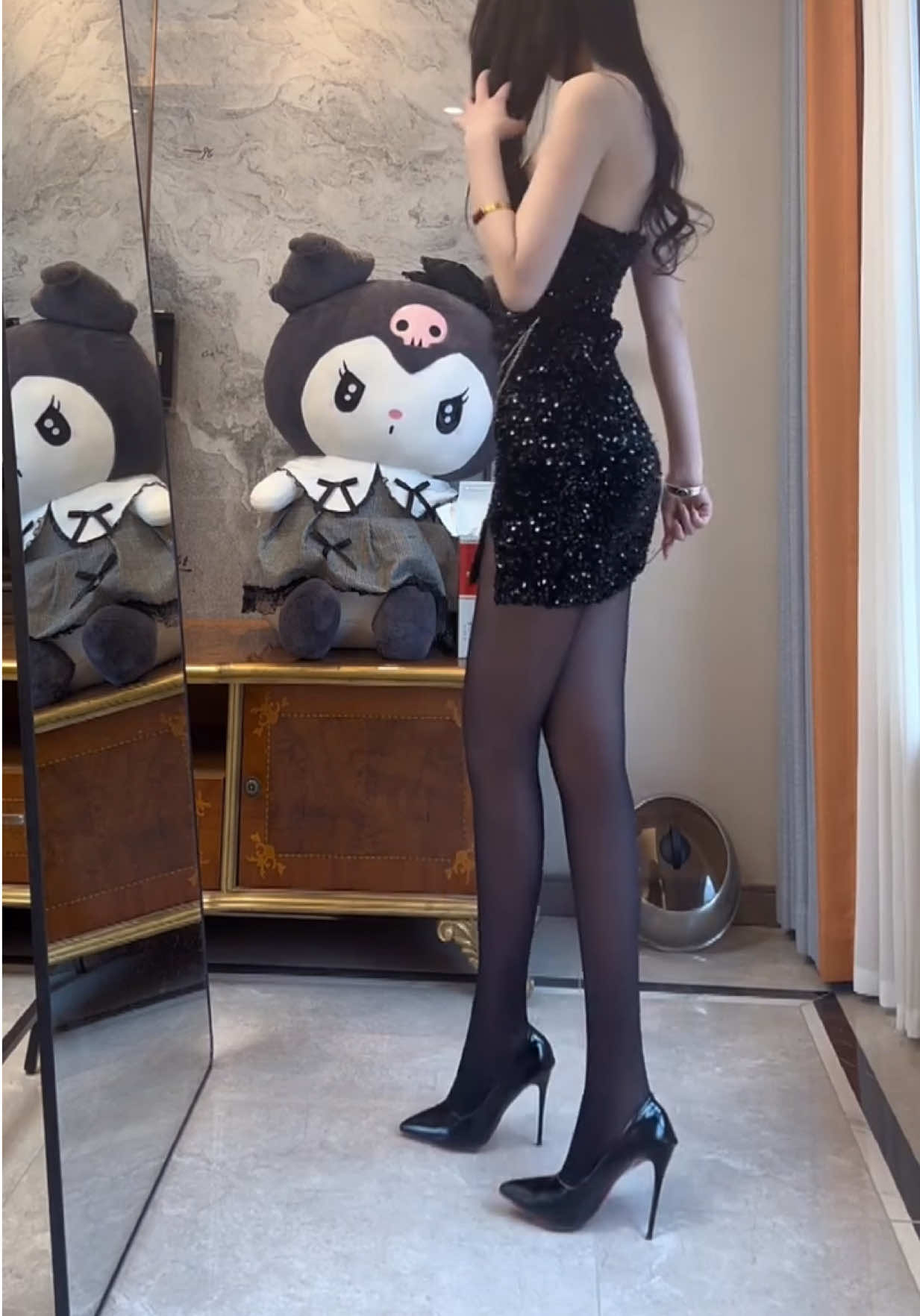 The black sequined strapless mini dress, paired with black stockings and high heels, creates a glamorous look, with the Kuromi plush toy adding a cute touch to the scene.#chinesegirl #ThanhThoiLuotTet #xuhuong #trending #trend 