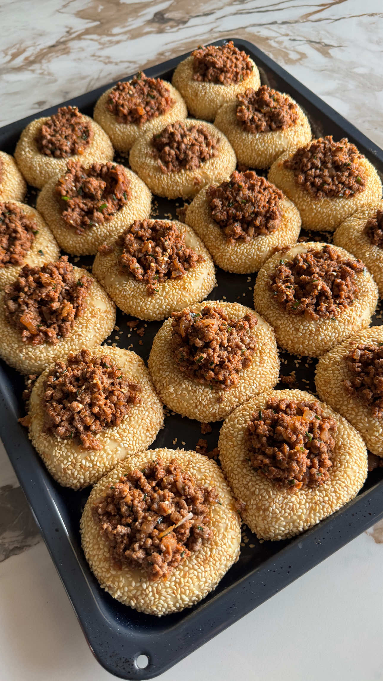 מצרכים: לבצק: (בכוס חד פעמית לשתייה קרה) 	•	1 קילו קמח 	•	25 גרם שמרים טריים 	•	1 כוס סוכר 	•	3 כוסות מים 	•	1 ביצה 	•	1 כוס שמן 	•	1 כף מלח למילוי: 	•	1 קילו בשר טחון 	•	1 בצל גדול קצוץ 	•	חצי צרור עירית קצוצה 	•	3 כפות רסק עגבניות 	•	1 כף סוכר 	•	1 כף פפריקה 	•	מלח ופלפל לפי הטעם לציפוי: 	•	קערה עם מים וסילאן (מעט סילאן לתוך המים) 	•	סומסום ⸻ אופן ההכנה: 	1.	בקערת מיקסר שמים את כל מצרכי הבצק מלבד המלח ולשים כ-8 דקות. 	2.	מוסיפים את המלח ולשים עוד כשתי דקות. 	3.	מכסים את הבצק ונותנים לו לתפוח עד להכפלת הנפח. 	4.	בינתיים מכינים את המילוי: מטגנים את הבצל עם הבשר עד שכל הנוזלים מצטמצמים לחלוטין. 	5.	מכבים את האש, מוסיפים את הרסק, הסוכר, הפפריקה, המלח, הפלפל והעירית, ומערבבים היטב. 	6.	לאחר שהבצק תפח, מחלקים אותו לכדורים של כ-80 גרם כל אחד. 	7.	טובלים כל כדור בתערובת מים וסילאן, מצפים בסומסום ומניחים בתבנית מרופדת בנייר אפייה. 	8.	נותנים לכדורים לתפוח כ-30 דקות. 	9.	בעזרת כוס יוצרים גומה במרכז כל כדור וממלאים בתערובת הבשר. 	10.	אופים בתנור שחומם מראש ל-170 מעלות כ-25–30 דקות, עד שהמאפים זהובים ומושלמים #bakedgoods #homemadebread #savorybuns #meatbuns #stuffedbread                         