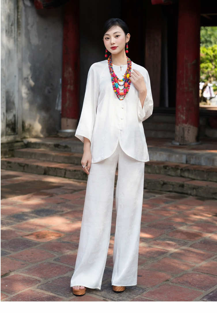 Từ độ sớm mai, khi nắng vừa chạm lên kén tằm, sợi tơ đã thức giấc, mảnh mai mà bền bỉ, thanh khiết như tấm lòng người thợ dệt. Bạch Liên Tâm ra đời trong hơi thở ấy, nơi từng sợi tơ được vun đắp bằng sự tĩnh tại và tinh tế, kết dệt thành lớp lụa óng ánh, mượt mà như dòng suối xuân. Phom dáng thướt tha, tay loe nhẹ như cánh sen khẽ lay trong gió, cúc tròn truyền thống e ấp mà nền nã, tất cả hài hòa lại thành dáng hình giai nhân Á Đông dịu dàng, đoan trang mà vẫn ánh lên khí chất riêng biệt.