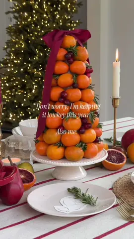 Proceeds to make an orange topiary 🤪 How to make this centerpiece— 1. Wrap a 12” styrofoam cone with Saran Wrap to make it food safe.  2. Poke the dull end of a toothpick into the side of the orange. Attach the orange to the cone using the toothpicks sharp end. Repeat this step all around the base of the cone.  3. Start the next layer by stacking the orange above where two oranges meet, so the next layer is offset. Repeat this step until you get to the top.  4. Start adding cranberries into the gaps using the same toothpick method as the oranges. Add them in clusters and singles to look like ornaments. 5. Fill the remaining gaps with sprigs of rosemary.  6. Top with a bow! You can tie a bow to a toothpick and add it to the center of the top orange.  #christmas #christmasdecorating #christmasdecor #fyp #fypシ 