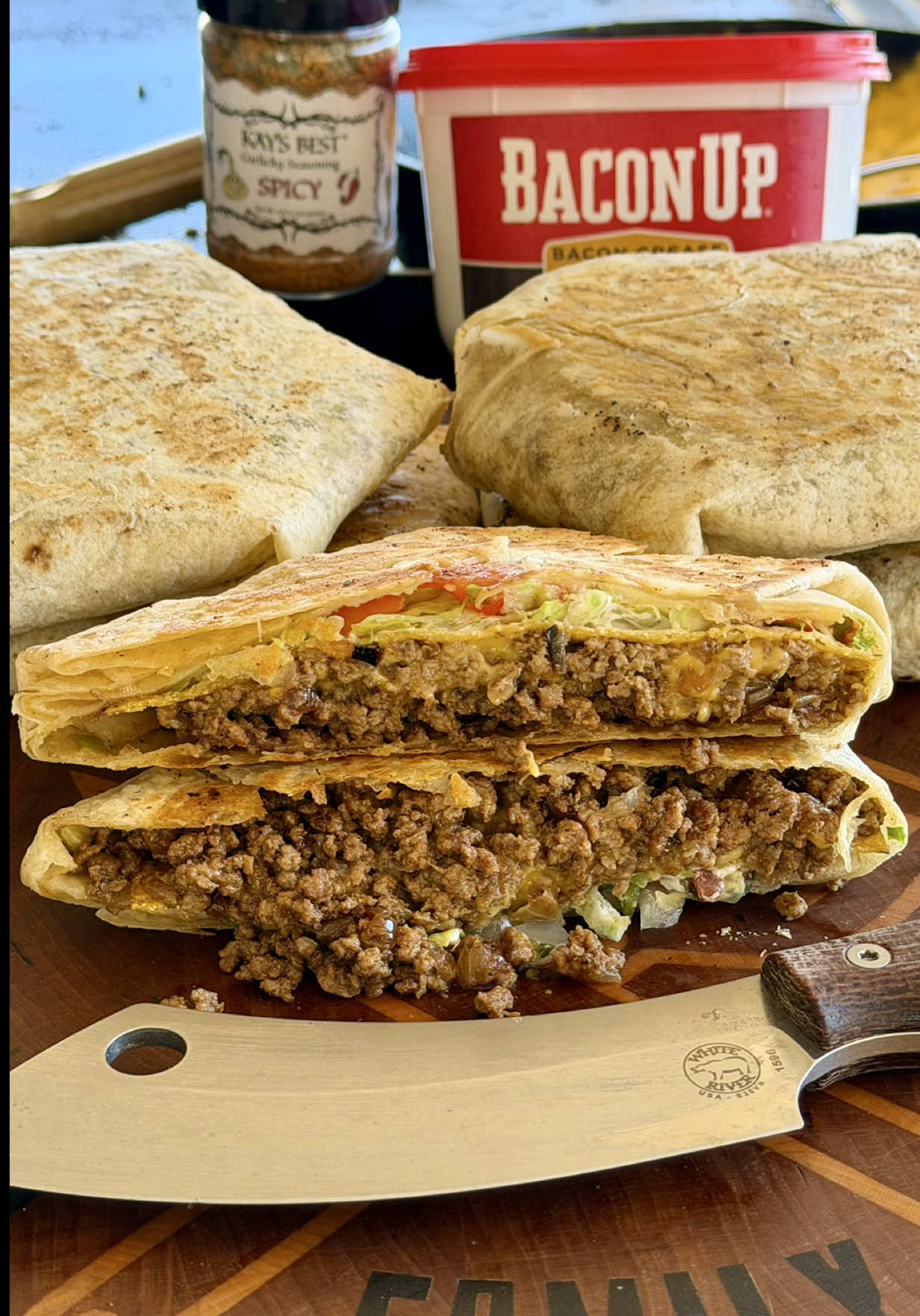 NOT Taco Bell Crunchwrap Supreme  Griddle set on medium heat and greased with bacon fat. Cook up a diced sweet onion seasoned with @kaysbestspice Spicy Garlic. Add 2 lbs of ground beef from @k4gourmetbeef and cook it all together. When it’s about done, season it with your favorite taco seasoning and a bit more of that Kay’s. Build on a 12” flour tortilla with a scoop of that taco meat, queso, tostada shell, Mexican crème or sour cream, shredded lettuce and pico de gallo. Wrap it in a circle as seen in video and get it back on the griddle to toast over low heat.  Recipe should yield 6 Crunchwraps give or take.  Nacho Cheese recipe: 1 block cheddar cheese 16 oz heavy cream 1 1/2 cups shredded sharp cheddar  In smoker or oven for about 30min stirring every 10 Or just buy a can of nacho cheese at the grocery store.  #tacobell #griddle #jesus @Bacon Up Bacon Grease @Weber Grills @K4Ranches 