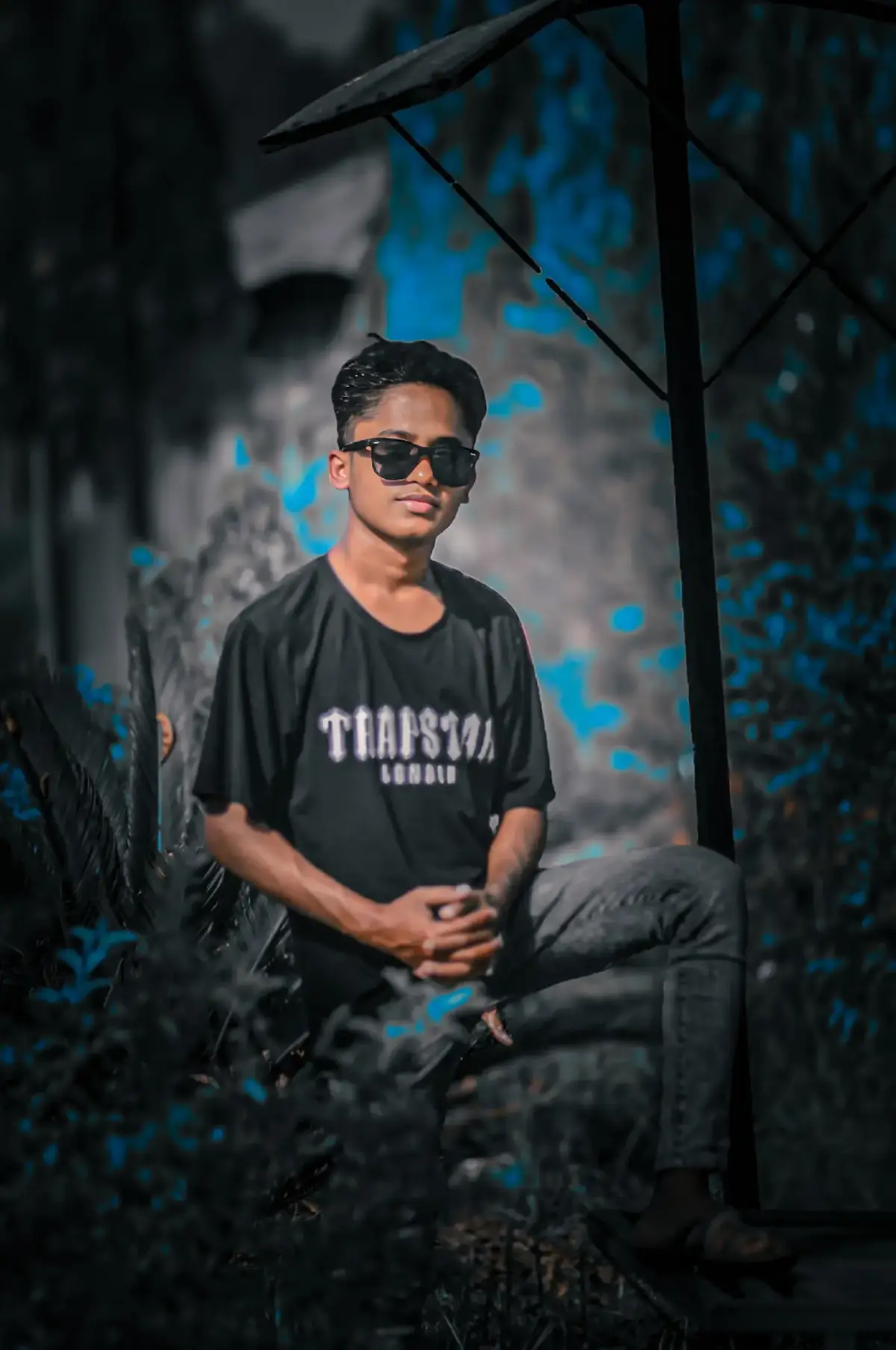 #typシ👉 #rypppppppppppppppppシtypyee 🦋💫:A young man sitting stylishly on tall grass in an orchard/garden with large trees in the background. He will be wearing a red and white striped Cuban collar shirt, blue jeans, and white Nike Air Max sneakers. He should have a black watch on his wrist, stylishly arranged hair, and a clear face.