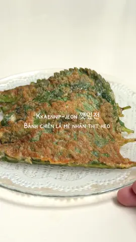 🥢 Kkaennip-jeon 깻잎전 Bánh chiên lá mè nhân thịt heo  Nguyên liệu:  15-20 lá mè (perilla leaves)  1-2 trái trứng đánh tan  bột mì hoặc bột bắp  🌟Phần nhân:  300g thịt heo xay  1/2 củ hành tây xắt hạt lựu 3-4 tép tỏi băm nhuyễn 1-2 trái ớt sừng, bỏ hột & xắt nhỏ  1/2 tsp muối 1/2 tsp tiêu 1/2 tsp hạt nêm  1 tsp đường  1 tbsp nước tương  chút xíu trứng đánh để tạo độ kết dính  🌟Cách làm:  Rửa sạch lá mè, để ráo hoặc thấm khô  Đánh tan trứng và cho khoảng 1-2 tbsp vào hỗn hợp nhân  Trộn đều các nguyên liệu trong phần nhân, dùng đũa quết theo 1 chiều tới khi hỗn hợp mịn dẻo Áo qua một lớp bột mỏng trên lá mè (cả 2 mặt nha), cho nhân vào giữa vào ghép lại (đơn giản lắm), chỗ này tuỳ gu bánh nhiều hay ít thịt cả nhà tự điều chỉnh theo ý nha  Làm lần lượt cho tới khi hết nhân và lá Nhúng từng bánh vào trứng, rồi đem chiên vàng hai mặt, để lửa vừa cho nhân bên trong chín đều nha.  Tới đây lấy ra ăn liền khi nóng là ngon nhất, có thể chấm thêm xì dầu, tương ớt nữa.  Một số lưu ý:  🌿Về nguyên liệu:  Lá mè: giao diện hơn giống lá tía tô nhưng nó là một loại rau thơm khác nha, nếu mọi người hay đi ăn nướng Hàn Quốc thì sẽ biết loại này, hay được dùng để cuốn thịt nướng ăn kèm Bạn có thể tìm mua lá mè ở các siêu thị Hàn như Lotte, Emart hoặc K Market Thịt: có thể thay bằng thịt bò hoặc gà xay, nếu muốn làm nhân chay thì dùng đậu hũ tán nhỏ ha Hành tây & ớt: có thể thay hoặc thêm hành tím, ớt chuông, hai thứ này giúp nhân ngọt và thơm hơn, đừng bỏ qua nhé  🌿Bảo quản:  Đây là một món siêu dễ bảo quản, khi ăn chiên lại vẫn ngon như mới, mọi người nhớ chiên chín và để nguội rồi cất hộp kín, bảo quản trong tủ lạnh được 3-4 ngày hoặc dưới 3 tháng trên ngăn đông nha :D #suenauan #comnhahomnay  