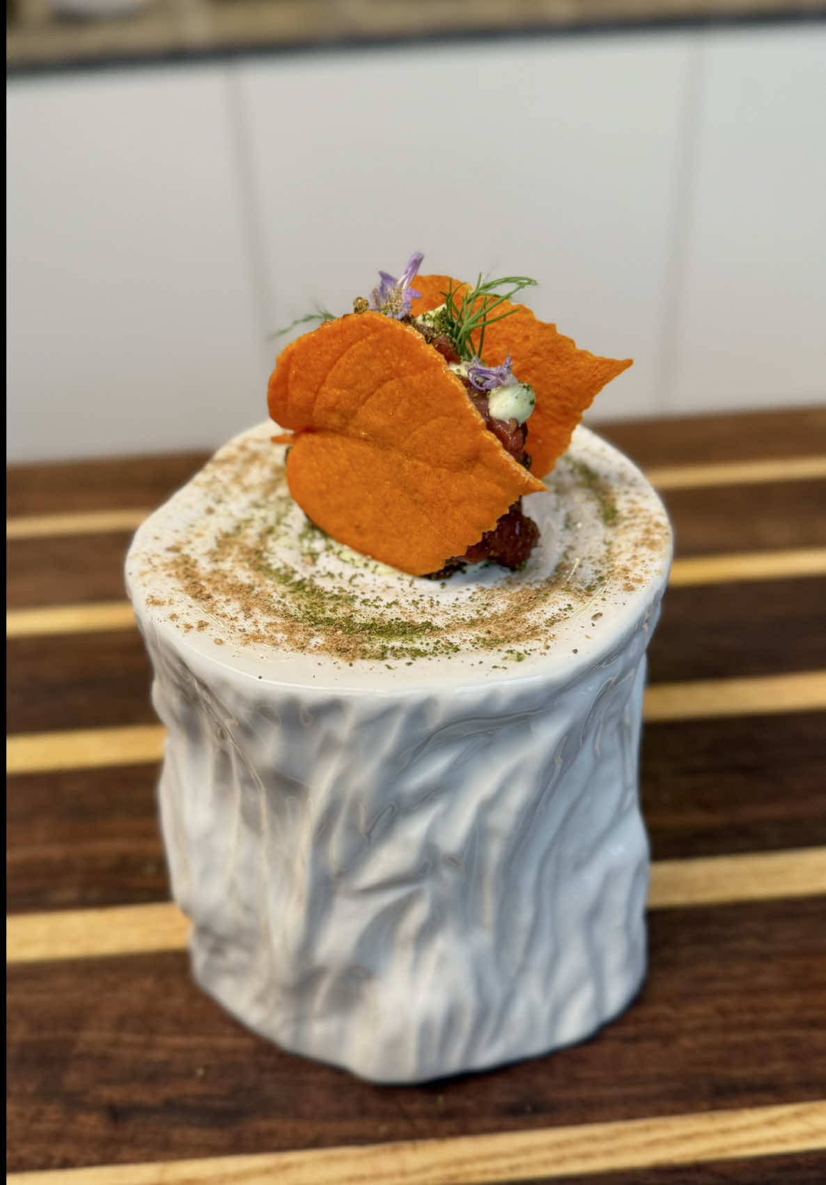 Finger d'Autunno🍂 Ingredienti: • Tartare di manzo 250 g • Polvere di fungo 20/25 g • Polvere di alloro 8/10 g • Sale e pepe q.b. • Olio EVO q.b. Per la maionese all'aneto: • 80g di tuorlo (pastorizzato) • Estratto di aneto q.b. • 180g di olio di semi all'aneto • Sale q.b. Per la maionese al rafano: • 180g di olio di semi al rafano • 80g di tuorlo pastorizzato • Sale q.b. Preparazione: Per le tuille, si frullano tutti gli ingredienti fino a ottenere un composto omogeneo. Si stende poi il composto negli stampi scelti e si inforna a 160°C per circa cinque minuti. Successivamente, si modellano le tuille nella forma desiderata e si rimettono in forno per altri dieci minuti a 65°C, lasciandole poi asciugare per circa un'ora per ottenere una consistenza croccante e stabile. Per la tartare, si taglia il manzo prima a fette, poi a strisce e infine a cubetti regolari. Si condisce con sale, olio extravergine, pepe e le polveri di alloro e funghi, mescolando delicatamente per non compromettere la consistenza della carne. Per la maionese all'aneto, si emulsionano i tuorli pastorizzati con l'olio di semi aromatizzato, aggiungendo alla fine l'estratto di aneto. Si regola di sale e si tiene da parte. La maionese al rafano si prepara nello stesso modo: si emulsionano i tuorli con l'olio di semi al rafano e si aggiusta di sale, fino a ottenere una consistenza liscia e stabile. A questo punto si può comporre il piatto: si dispone la tartare, si aggiungono le due foglie di tuile e si completano con gocce alternate delle due maionesi. Si finisce con una leggera spolverata di polvere di alloro e funghi e con qualche germoglio fresco per dare colore e freschezza al piatto. #danielerossichef #ricettedelgiorno #beef #tartare #chef 