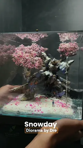 Snowfall Requiem– Khúc Tuyết Rơi Dưới tán anh đào đang nở những bông đầu mùa, giữa lớp tuyết cuối đông còn vương lại, người lính nhỏ bé đứng trước người bạn chiến binh khổng lồ đã ngủ quên theo năm tháng. Bộ giáp robot sứt mẻ, phủ đầy băng giá và rêu cũ, như ghi lại từng trận chiến mà nó đã âm thầm gánh chịu. Hôm nay, khi mùa đông dần rút lui và sắc xuân khẽ chạm vào đất trời, người lính trở về, lặng lẽ nhìn lại “đồng đội” từng kề vai sát cánh. Không còn tiếng động cơ, không còn ánh thép rực lửa – chỉ còn lại sự bình yên và một lời chào muộn màng giữa hai kẻ từng cùng nhau viết nên huyền thoại. #dregreendecor #diorama #dioramamaker #mecha #moshowtoys 