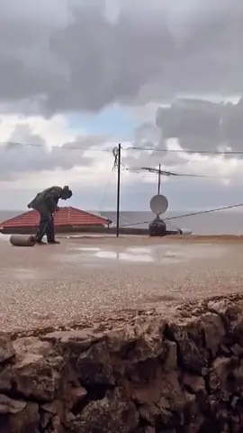 في ظل قطرات المطر التي تتساقط بلطف، نجد رجلاً كبيرًا في السن يمشي ببطء، عيناه تراقبان الأرض، وابتسامته تظهر من خلال قطرات المطر التي تلمع على وجهه. إنه لحظة من التأمل والسلام، حيث يبدو وكأنه يغرق في ذكريات الماضي، ويستمتع باللحظة الحالية. المطر يغسل روحه، ويعيد له الحيوية،  ويذكره بجمال الحياة البسيطة.