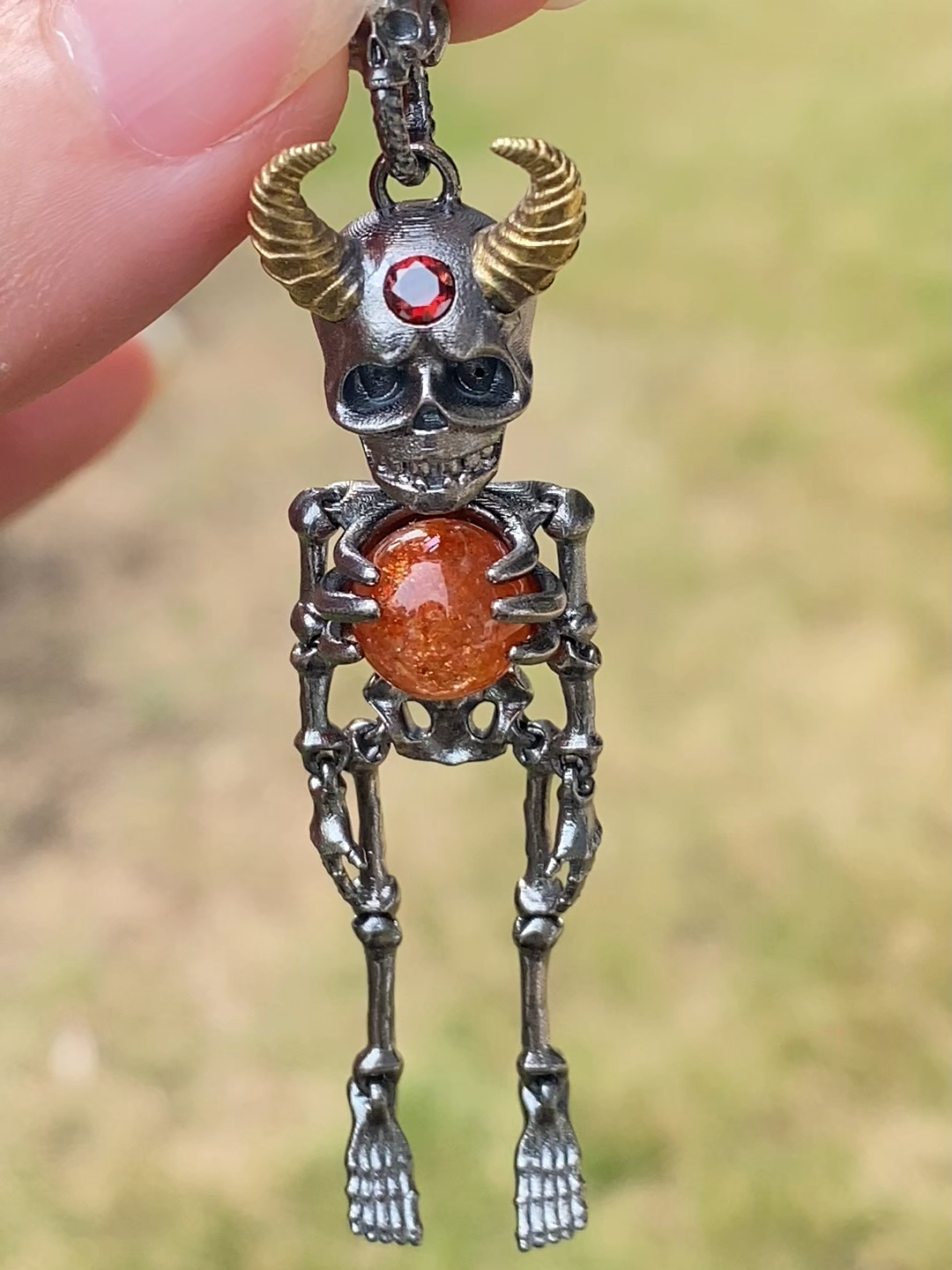 Un pendentif squelette artisanal en argent 925, orné d'une pierre de soleil naturelle flamboyante. Ses cornes dorées symbolisent la puissance, tandis que la pierre orange intense représente l’énergie vitale et la protection. Chaque détail est sculpté à la main, offrant un style mystique, audacieux et unique — parfait pour ceux qui adorent les bijoux ésotériques, gothiques et artisanaux. ✨ Un bijou qui attire le regard, idéal pour les fêtes, les soirées et les amateurs de pièces hors du commun. 🎃 Halloween / Fête des Morts 🎄 Noël 🎁 Cadeau unique pour les collectionneurs ✨ Cadeau mystique / ésotérique 💑 Cadeau pour couple gothique 🧙‍♂️ Fans de fantasy / dark style#bijouxGothique　#bijouxGothiquesFrance　#styleGothique　#artGothique #pendentifSquelette　#collierSquelette　#bijouxSquelette #bijouxÉsotériques　#styleÉsotérique　#bijouxMystiques　#bijouxOccultes #bijouxFantasy　#bijouxFantaisieFrance　#bijouxDark #pendentifDémon　#bijouDémoniaque　#bijouxMagiques #pierredesoleilNaturelle　#pierredesoleil　#sunstoneJewelry #grenatNaturel　#grenatBijoux　#grenatRouge #bijouxArtisanaux　#bijouArtisanalFrance　#artisanBijoux #bijouxFaitMain　#handmadewithlove　#bijouUnique #collierArtisanalArgent　#bijouxArgent925　#argent925 #bijouOriginal　#idéeCadeauNoël　#cadeauOriginal #cadeauFrance　#cadeauFemme　#cadeauHomme #bijouxSteampunk　#styleSteampunk #bijouHalloween　#cadeauHalloweenFrance #bijouxSombre　#bijouxOccultesFrance #bijouxTalisman　#amuletteBijoux　#bijouxAmulette #bijouxSculpture　#bijouxArtFrance #bijouxGemmeNaturelle　#bijouxPierreNaturelle #bijouxCréateur　#créateurBijouxFrance #bijouGeek　#bijouxFantastiques #designBijoux　#bijouxDeCaractère #bijouxPourElle　#bijouxPourLui #collierLong　#pendentifArt #bijouStatement　#bijouFashion #bijouxFranceShop　#tendanceBijouxFrance