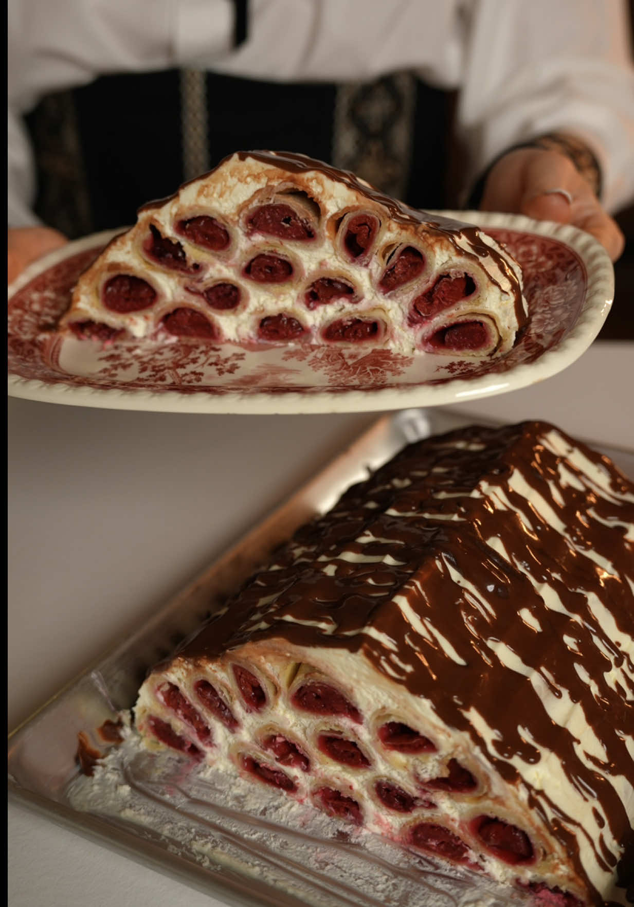 Монастирська ізба чи Смерекова хата? 🍒 Тісто: - Борошно — 380 г - Вершкове масло 82,5% (заморожене) — 200 г - Сметана 20% — 200 г - Цукор — 1 ст. л. Для начинки: - Вишня — 1 кг - Цукор — 80 г - Крохмаль — 80 г Для крему: - Сметана 20% (жирна) — 700 г - Вершки 33% (холодні) — 300 г - Цукрова пудра — 250 г - Ванільний цукор — 10 г - Для декору: чорний шоколад + вершки — 50 г + 50 мл 1. Заморожене масло натерти на терці. Змішати з борошном і цукром до стану крихти. Додати сметану й швидко замісити м’яке тісто. Довго не місити — лише поєднати інгредієнти. Загорнути тісто в плівку та охолодити 40–60 хв. 2. Вишню розморозити, злити зайву рідину, змішати з цукром. Додати крохмаль і добре перемішати.  3. Тісто поділити на 15 частин. Кожну частину розкачати в прямокутник максимально тонко (~20×10 см). Викласти смужку вишневої начинки по центру. Щільно згорнути в рулет-трубочку, защипнути краї. 4. Викласти трубочки швом донизу. Випікати при 190°C приблизно 20–25 хв, до золотистості — орієнтуватися на колір. Повністю охолодити. 5. Якщо сметана дуже рідка — попередньо відцідити її через марлю 1–2 години. Холодні вершки збити з цукровою пудрою до м’яких піків. 6. Додати сметану й ванільний цукор. Акуратно перемішати лопаткою або коротко міксером.  7. Форму змастити кремом. Викладати трубочки шарами, кожен шар змащуючи кремом (5–4–3–2–1). Верх і боки також добре змастити кремом, сформувати форму хатки. Відправити торт у холодильник на ніч. 8. Вранці нагріти вершки до гарячого, але не киплячого стану. Додати шматочки шоколаду, перемішати до гладкої глазурі. Полити “хатинку” зверху. #смерековахата #монастирськаізба 