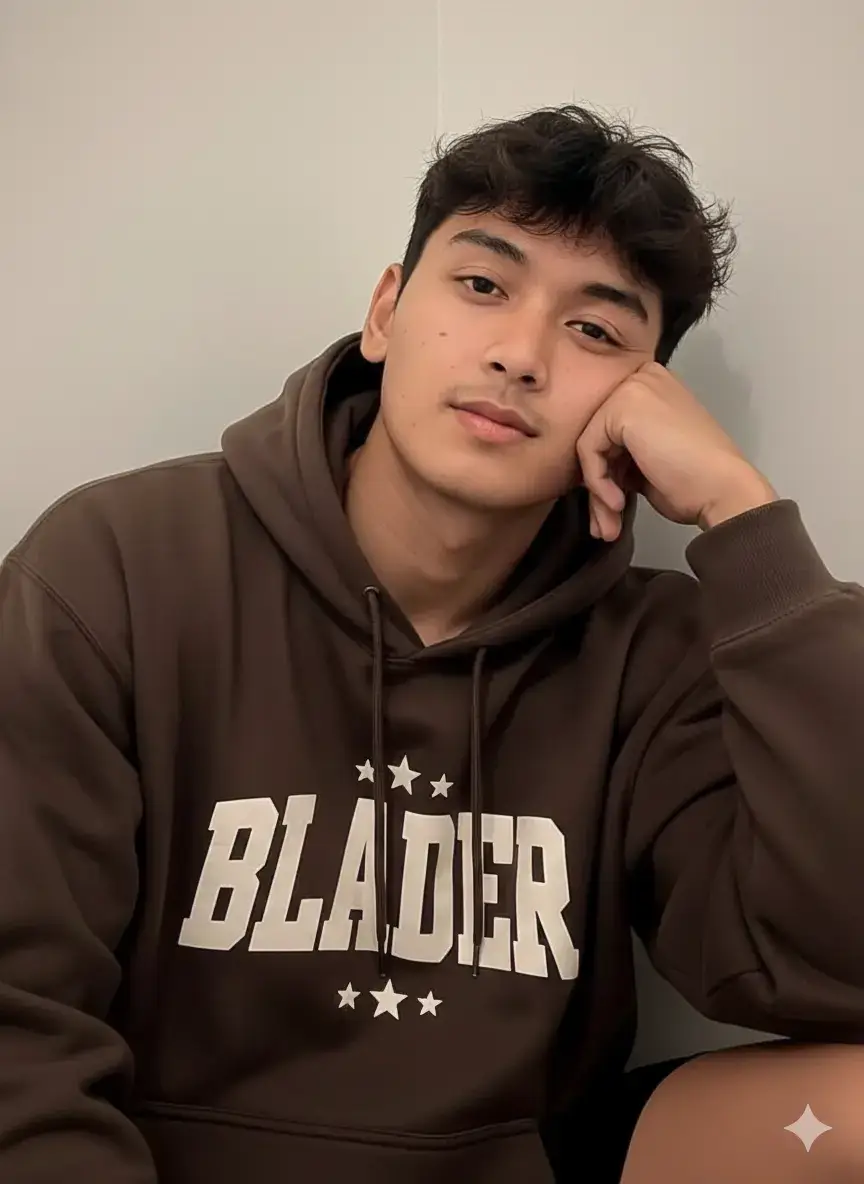 Prompt 👇 Foto selfie jarak dekat yang menangkap seorang pria muda Asia dengan kulit cerah dan fitur wajah lembut. Ia memiliki rambut tebal berwarna hitam kecokelatan yang sedikit berantakan, membingkai wajahnya. Tatapannya langsung dan tenang menghadap kamera dengan sedikit ekspresi melamun atau santai. ​Pria itu mengenakan jaket hoodie berwarna cokelat tua atau cokelat kopi yang oversized. Di bagian depan hoodie terdapat desain cetak yang besar, tampak seperti logo atau pola dekoratif berwarna krem atau putih gading dengan motif bintang atau huruf kapital yang besar. ​Ia menyandarkan kepala dan pipi kanannya pada tangan kanannya, dengan siku bertumpu di luar bingkai, memberikan kesan santai dan kasual. Posisi kamera dari sudut sedikit atas ke bawah (high angle), menonjolkan fitur wajahnya. ​Latar belakangnya minimalis, menunjukkan sudut dalam ruangan dengan warna dinding krem atau putih lembut. Pencahayaan di ruangan tersebut adalah cahaya lembut, merata, dan kekuningan, khas pencahayaan dalam ruangan pada malam hari, menciptakan suasana yang hangat dan akrab. #gemini #ai #prompt #fy #fyppppppppppppppppppppppp 