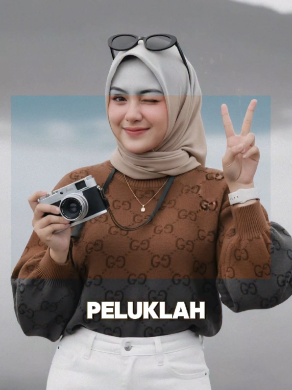 prompt  Buat potret foto realistis dari seorang wanita muda (wajah harus 100% sama persis dengan foto asli, tidak boleh diubah). Rambut: hijab beige rapih. Ia memakai kacamata hitam vintage berbentuk oval yang keren di atas kepala nya Riasan wajah: Makeup bergaya Korea – kulit tampak glowing dan licin seperti “glass skin”, dengan blush pink lembut pada pipi, eyeshadow cokelat muda bernuansa earthy, bulu mata panjang alami, dan alis lembut berbentuk natural. Bibir dibuat ombre dengan warna pink-rose, gradasi halus dengan tepi yang sedikit blur. Pakaian: Ia memakai sweater rajut berlengan panjang motif GG warna cokelat dengan lengan balon yang longgar. Bawahannya adalah celana jeans putih high-waist panjang. Ia mengenakan kalung tipis dengan liontin kecil, Apple Watch putih, yang terlihat elegan. Latar belakang: Pemandangan pegunungan dengan lautan kabut yang indah. Pose & ekspresi: Ia berdiri sambil menyipitkan  satu mata lucu, suasana hati ceria. Satu tangan memegang kamera leica , dan tangan lainnya diangkat sambil menunjukkan pose dua jari (peace sign) dengan gaya bahagia. Kepala sedikit dimiringkan, memancarkan kesan manis sekaligus menggoda. Hasil gambar seperti Menggunakan Canon EOS R5 dengan lensa RF 85mm f/1.2L full-frame, aperture f/1.4, resolusi 8K, menghasilkan ketajaman dan realisme tingkat profesional. #CapCut 