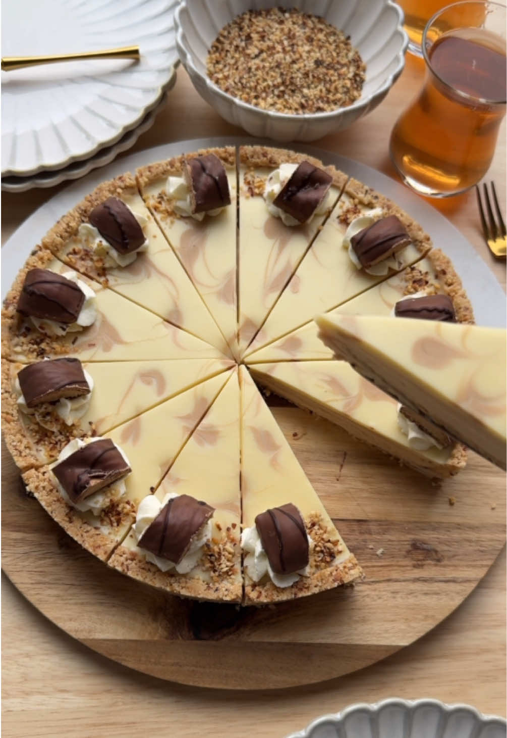 BUENO TART (NO BAKE) #nobake #hazelnut #dessert #fyp  COOKIE BASE 130 g unsalted butter 140 g petit beurre biscuits 30 g finely chopped hazelnuts CREAM 350 g mascarpone 140 g hazelnut spread TOPPING 60 ml heavy cream (unwhipped) 125 g white chocolate 20 g hazelnut spread GARNISH Whipped cream Finely chopped hazelnuts Chocolate Melt the butter and let it cool slightly. Finely grind the petit beurre biscuits in a food processor. Place the crushed biscuits, hazelnuts, and melted butter in a large bowl. Mix well. Line a springform pan with baking paper. Spread the biscuit mixture over the bottom and press it down firmly with the back of a spoon, taking the edges slightly up for depth. Chill briefly in the refrigerator. Place the mascarpone and hazelnut spread in a deep bowl and mix for 1 minute, or until fully combined. Spread the creamy mixture evenly over the biscuit base. Heat the heavy cream until just below boiling. Add the white chocolate and let it sit for 1 minute. Stir until smooth to create a ganache, and let it cool slightly. Pour the ganache over the cream layer. Pipe some hazelnut spread on top and use a toothpick to create a pretty swirl pattern. Cover and refrigerate for at least one night to set. Cut into equal slices. Garnish with whipped cream, chopped hazelnuts, and chocolate if desired. Bismillah, enjoy! Tips: * The firmer you press the biscuit base, the better it will hold when slicing. Use the back of a spoon for a clean finish. * Mix the mascarpone and hazelnut spread for only 1 minute. Overmixing can make the mixture too thin. * Let the ganache cool slightly before pouring. If it’s too warm, it may melt the cream layer and cause the layers to blend. * Place the 20 g hazelnut spread in a small piping bag (or zip bag with a tiny cut). This gives you neat lines and a beautiful swirl pattern. * Use a warm knife for slicing. Dip the knife in hot water, dry it, and cut. * Repeat between each slice for perfectly clean cuts. * This tart can be stored in the fridge for 3–4 days. The biscuit base stays nice and firm. Prep Time Preparation: 20–25 minutes Chilling: at least 6 hours (preferably overnight)