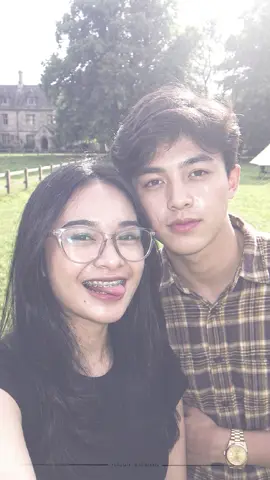 prompt Gemini ai bareng pasangan, ai trend terbaru dan cukup di copy paste aja. Pria dan Wanita (referensi wajah, telinga, hidung, mulut, orang dari gambar pertama, realitas virtual 100%) Ambil kamera belakang, bidikan close-up wajah, bidikan setengah badan, lensa RF 85mm, full frame, aperture f/1.4, resolusi hingga 8K, memberikan kontras realistis profesional, wajah menggunakan flash kuat gaya kamera digital 2000-an, cahaya kabur, menonjolkan wajah tenang dan suasana segar seperti foto snapshot awal 2000-an. Waktu siang hari, cahaya fase memancar ke wajah, dan kulit memantulkan cahaya lembut, banyak butiran. Cahaya mengenai kulit, membuat kulit cerah, bersih, putih, berkilau, halus. Menggunakan behel gigi berwarna abu-abu gelap. Wanita muda Rambut panjang hitam/cokelat tua dengan poni samping tipis. Mengenakan baju Kaus V-neck biru tua atau navy. Memakai kalung dengan liontin huruf D berwarna emas, Memakai topi baseball navy dengan huruf D. Dan pria di sampingnya mengenakan baju kaos biru napndengan aksesoris jam tangan rolex, kalung berbentuk love. 🌳 Latar belakang: • Tempat yang memiliki karakteristik padang rumput atau taman. • Elemen: • Tanah: Ada rumput hijau. • Pagar: Ada pagar kayu rendah atau deretan pohon sebagai pembatas di kejauhan. • Pohon: Ada pohon besar dan bangunan bergaya eropa yang terlihat di kejauhan. • Aktivitas: Tampak seperti tempat berkemah atau camping, karena ada tenda dan struktur kanvas putih yang didirikan di belakang di kejauhan ke kanan. Postur: Wanita Mengambil selfie dengan kamera belakang. Ekspresi: Melihat kamera sambil tersenyum, menjulurkan lidah dengan lucu. Ekspresinya tampak playful, imut, dan ramah. #geminiai #trendai #fyp #capcut #trending 