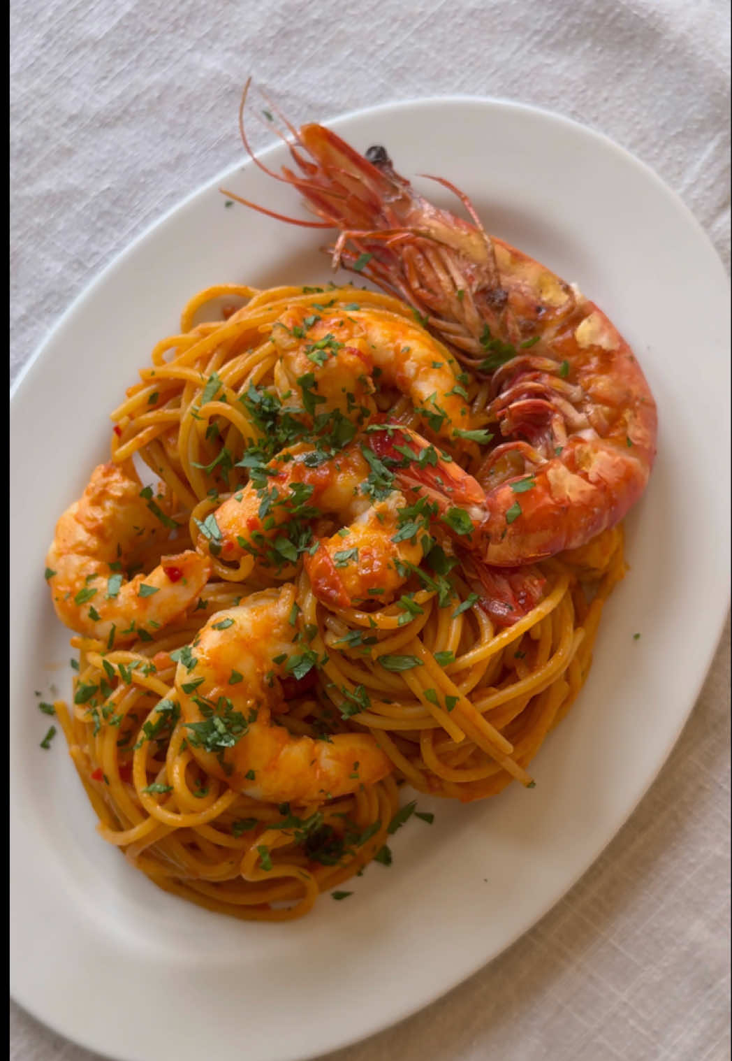 One of my top 3 date night dishes that I have in my arsenal. Prawn Linguine. Comment below if you’d like to see the other 2! This is such a brilliant technique for extracting as much flavour as you can from these delicious shellfish. Creating a stock and then letting the pasta soak it all up creates layer upon layers of beautiful flavour.  10 large prawns Butter 2 shallots, finely chopped 4 garlic cloves, chopped 2 tbsp tomato paste Small handful parsley stalks 1 small glass white wine Water 1 fresh red chilli, sliced 200g cherry tomatoes, halved 250g linguine Fresh parsley, chopped Salt Remove the heads and shells from the prawns, then devein them. Set the prawns aside. Melt a generous knob of butter in a pan and add the shells. Fry them until fragrant, then add one chopped shallot, half the garlic, half of the tomato paste and the parsley stalks. Cook it all down for a couple of minutes, then add the white wine and enough water to cover. Simmer gently for about an hour. Strain through a sieve and keep the liquid over a low heat to reduce and concentrate. In a separate pan, heat a little olive oil and quickly fry the prawns until just coloured, then lift them out. Add the remaining shallot, garlic and the sliced chilli. Cook until soft, then stir in a spoon of tomato paste. Add the cherry tomatoes and cook until they collapse into a rough sauce. Start adding the reduced prawn stock a ladle at a time until the sauce has a consistency a little runnier than tinned tomatoes. Season lightly. Boil the linguine in salted water until just bendy. We want it to be seriously al dente. Transfer the pasta straight into the sauce, tossing well and adding a splash of pasta water if the sauce needs loosening. Add some chopped parsley and then fold the prawns back in to warm through. Plate up and finish with a good sprinkling of chopped parsley.