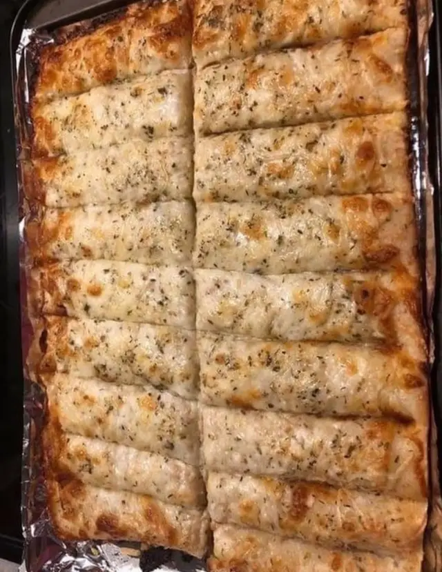 Homemade Cheesy Garlic Breadsticks Recipe 😋 Ingredients 1 tube of refrigerated pizza crust 1 Tablespoon butter melted 1 clove garlic crushed 3/4 cup grated mozzarella cheese feel free to add more! 1 Tablespoon Parmesan cheese 1 teaspoon dried oregano leaves optional Instructions Preheat the oven to 425F. Roll out the pizza crust onto a parchment lined baking sheet. Mix together the melted butter and crushed garlic, then brush it evenly over the entire pizza crust. Sprinkle the mozzarella and Parmesan cheeses evenly onto the pizza crust. Then sprinkle the dried oregano evenly on top. Before you bake, cut the cheese covered pizza crust into 16 equal rectangles using a pizza slicer or large knife. Bake for about 12 minutes until the cheese is melted, bubbly and slightly golden. Remove from the oven and cut the breadsticks again before serving.