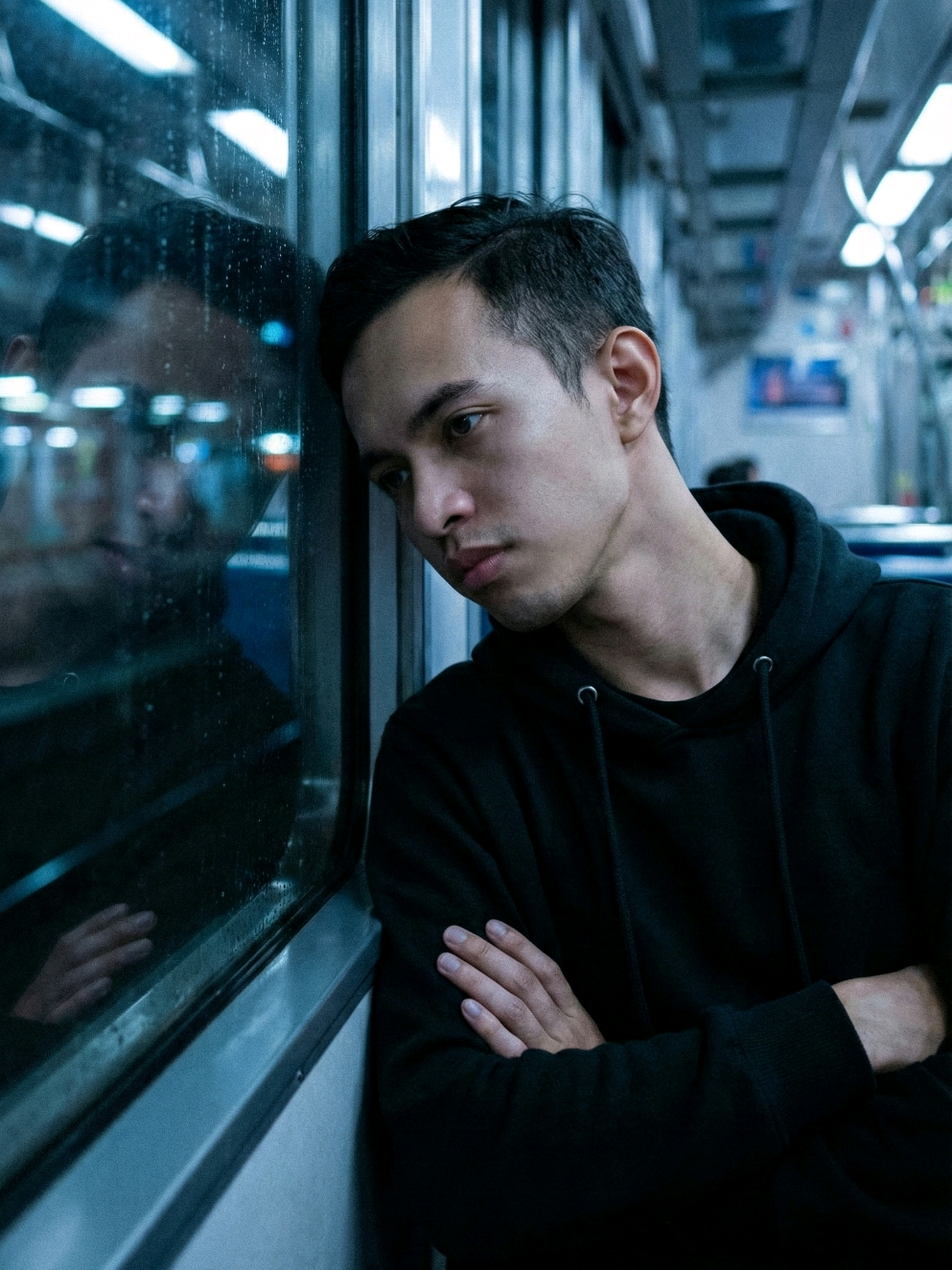 Prompt Ai pria sedang meratapi kesedihan di dalam kereta Buatkan gambar hyper-realistic, wajahnya sama persis dengan foto referensi (100% tanpa perubahan pada wajah, mata, struktur wajah, alis, hidung, bibir dan juga jangan merubah bentuk badan) Foto sinematik yang sendu menampilkan seseorang pria berhoodie hitam duduk sendirian di kereta di malam hari, bersandar di jendela dengan tangan terlipat. Adegan tersebut disinari redup dengan rona biru dingin, menciptakan suasana yang tenang dan introspektif. Pemandangan luar tampak kabur saat kereta bergerak, menciptakan efek gerakan lembut yang terpantul di jendela. Wajah orang tersebut sebagian diterangi oleh cahaya sekitar yang redup, menekankan suasana yang tenang dan reflektif. Diambil dari samping, kontras rendah, bayangan lembut, estetika film ISO tinggi. #fypage #fyp #fyppppppppppppppppppppppp #fypシ゚ #sad 