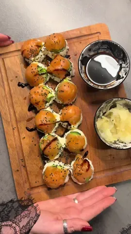 🍣 Суши в яичной коробке Ингредиенты: 	•	Красная рыба (лосось) 	•	Рис для суши 	•	Огурец 	•	Авокадо 	•	Сыр «Филадельфия» 	•	Листы нори 	•	Кунжут 	•	Соус терияки ⸻ Приготовление: На дно каждой выемки картонной коробки кладём кусочек красной рыбы, сверху выкладываем авокадо, затем огурец и сливочный сыр «Филадельфия». Всё это накрываем рисом для суши, слегка прижимая, чтобы слои держались. Сверху кладём нарезанные маленькими квадратиками листы нори. Аккуратно переворачиваем коробку на тарелку — получаются маленькие круглые «суши-шарики». Поливаем терияки и посыпаем кунжутом. #gilyova #рецепты #суши #роли 